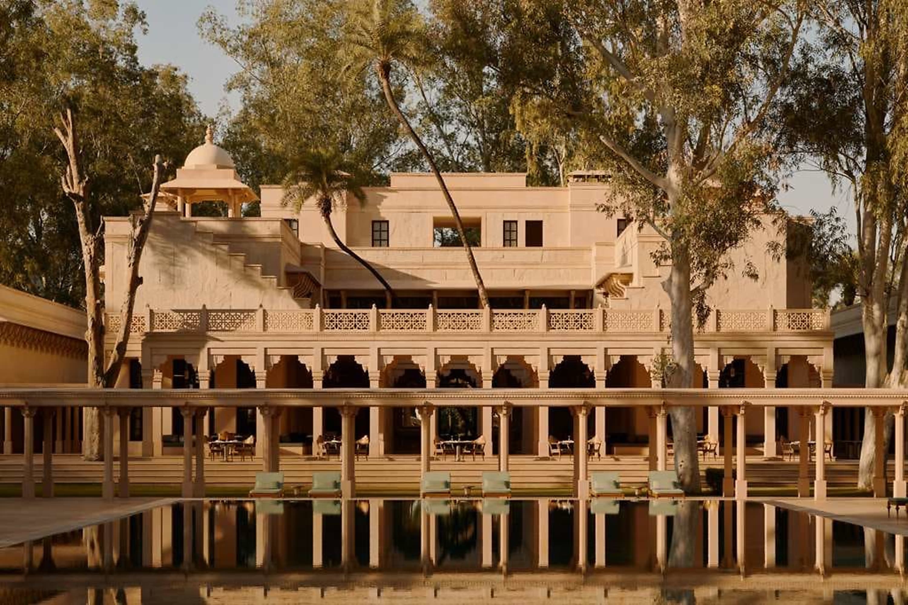 A pool with a mirror surface in front of intricate Indian architecture