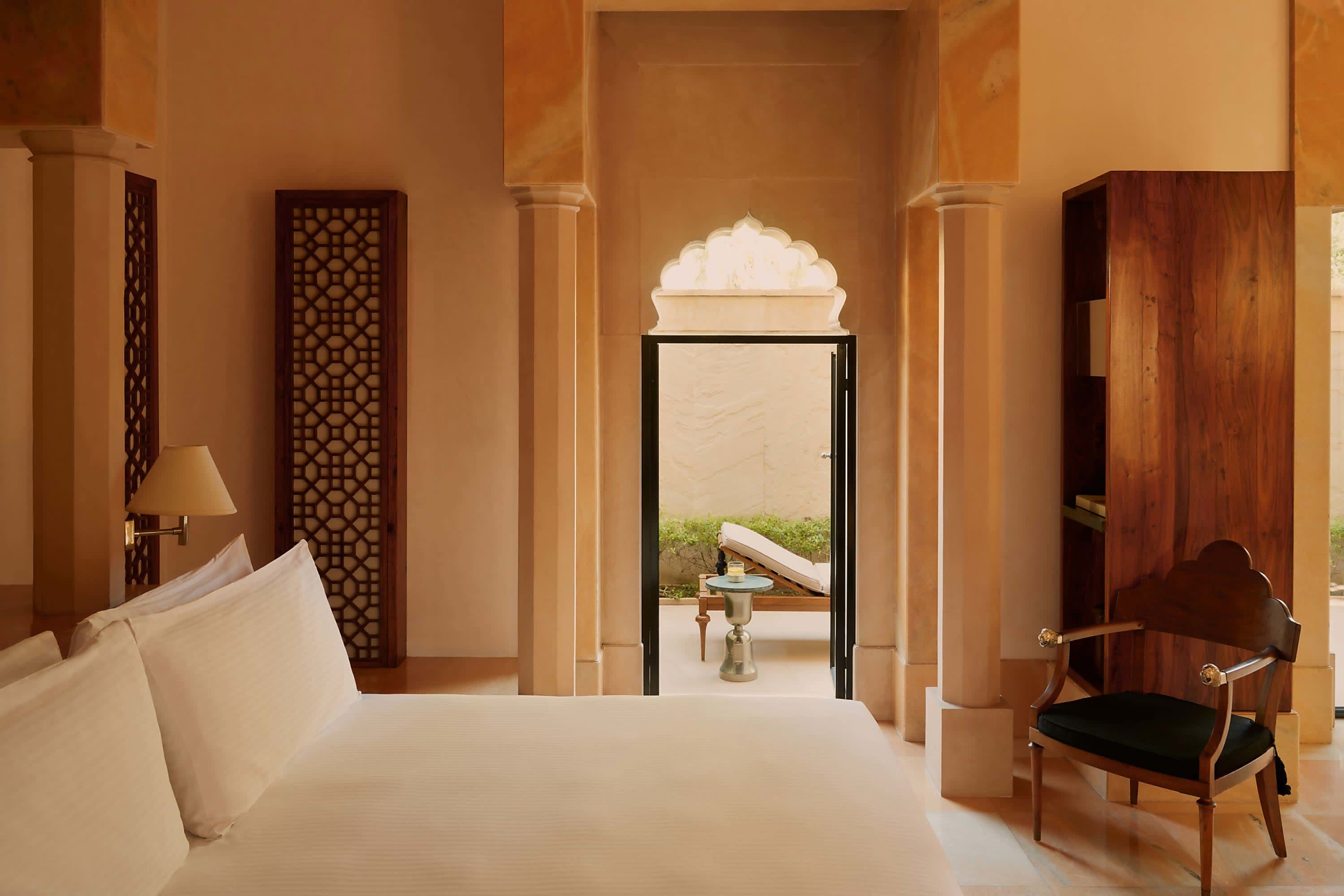 Minimalist but luxe hotel room with what appears to be a lounge chair through an open doorway