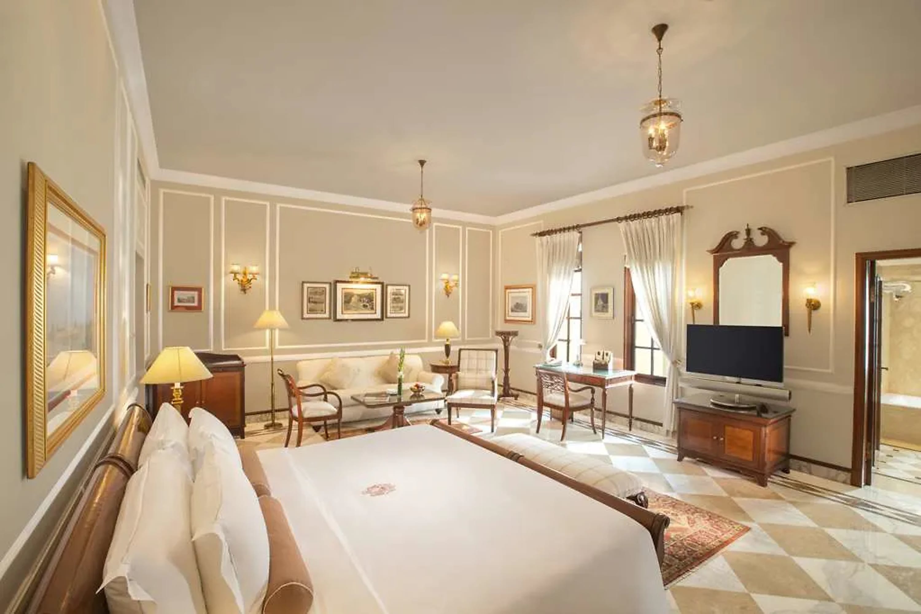Elegant hotel room with hardwood and gold accents, elegant drapes hang over the window but still allow plenty of natural light in