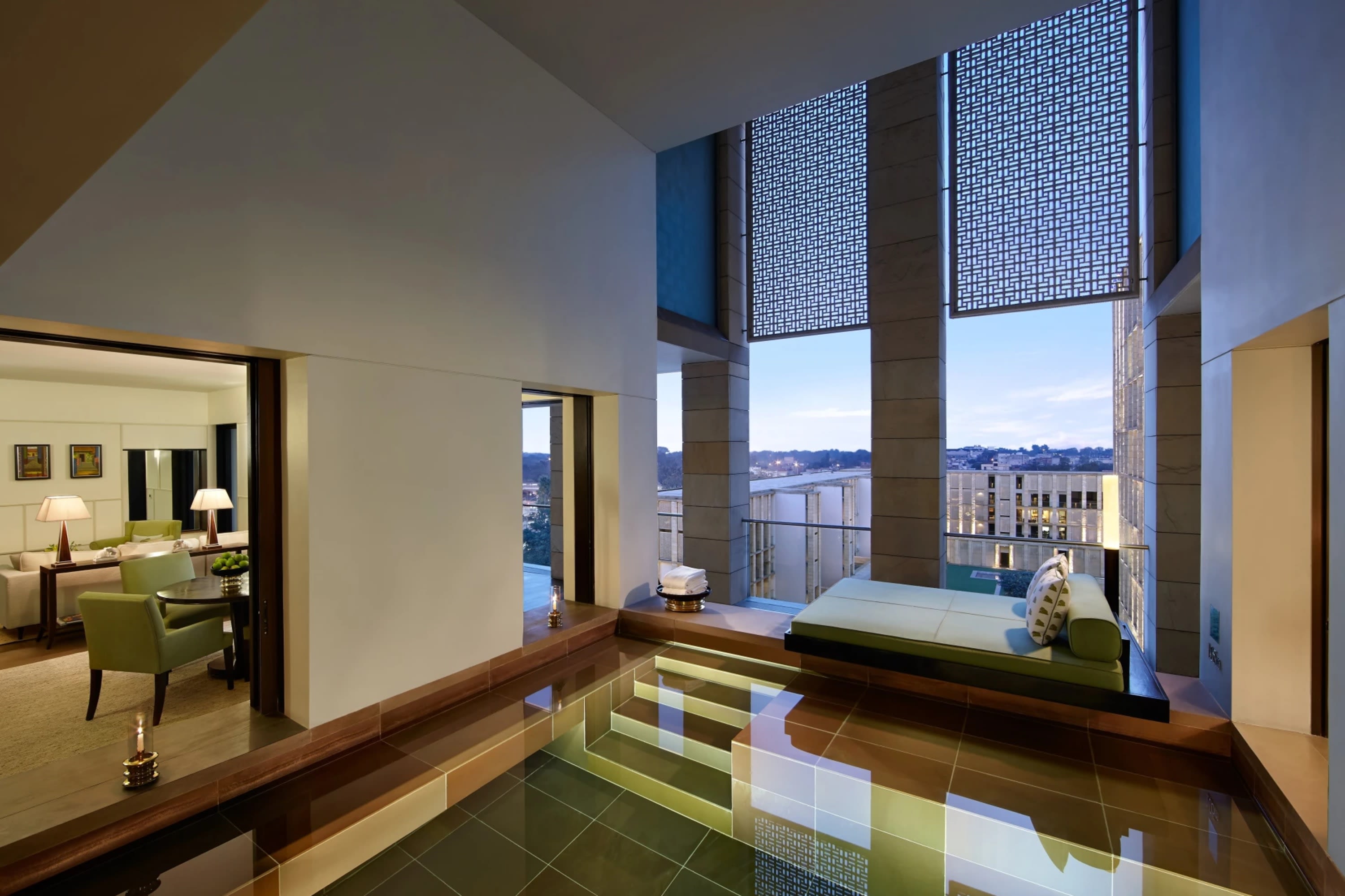 In-room pool next to a bed and floor-to-ceiling windows. Through a hallway, you can see a living room