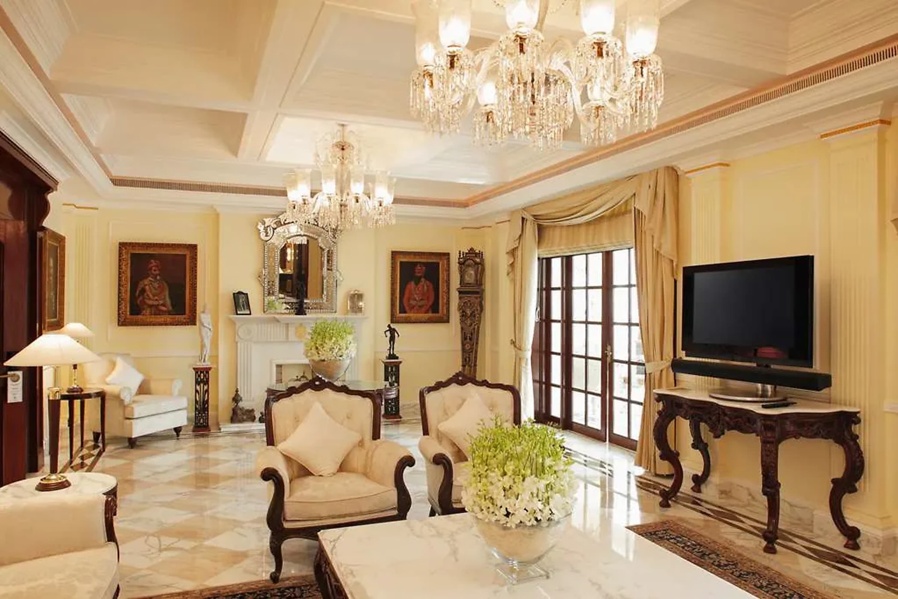 Vintage furnishings, elegant details like crystal chandeliers and fine Indian art fill a hotel living room with marble floors