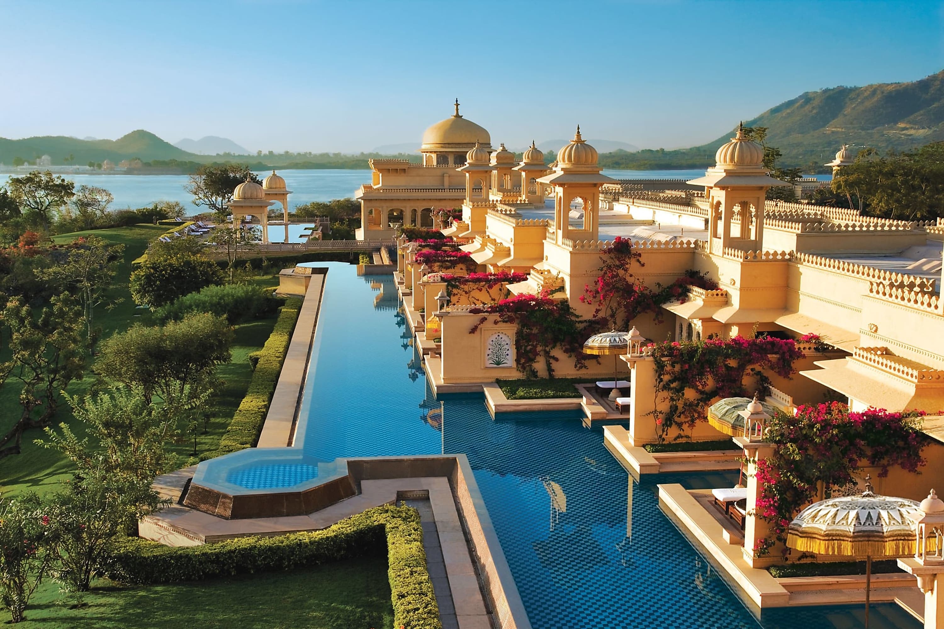 Grand palace-like hotel with a pool running along the edge of the building, offering immediate access from each hotel suite