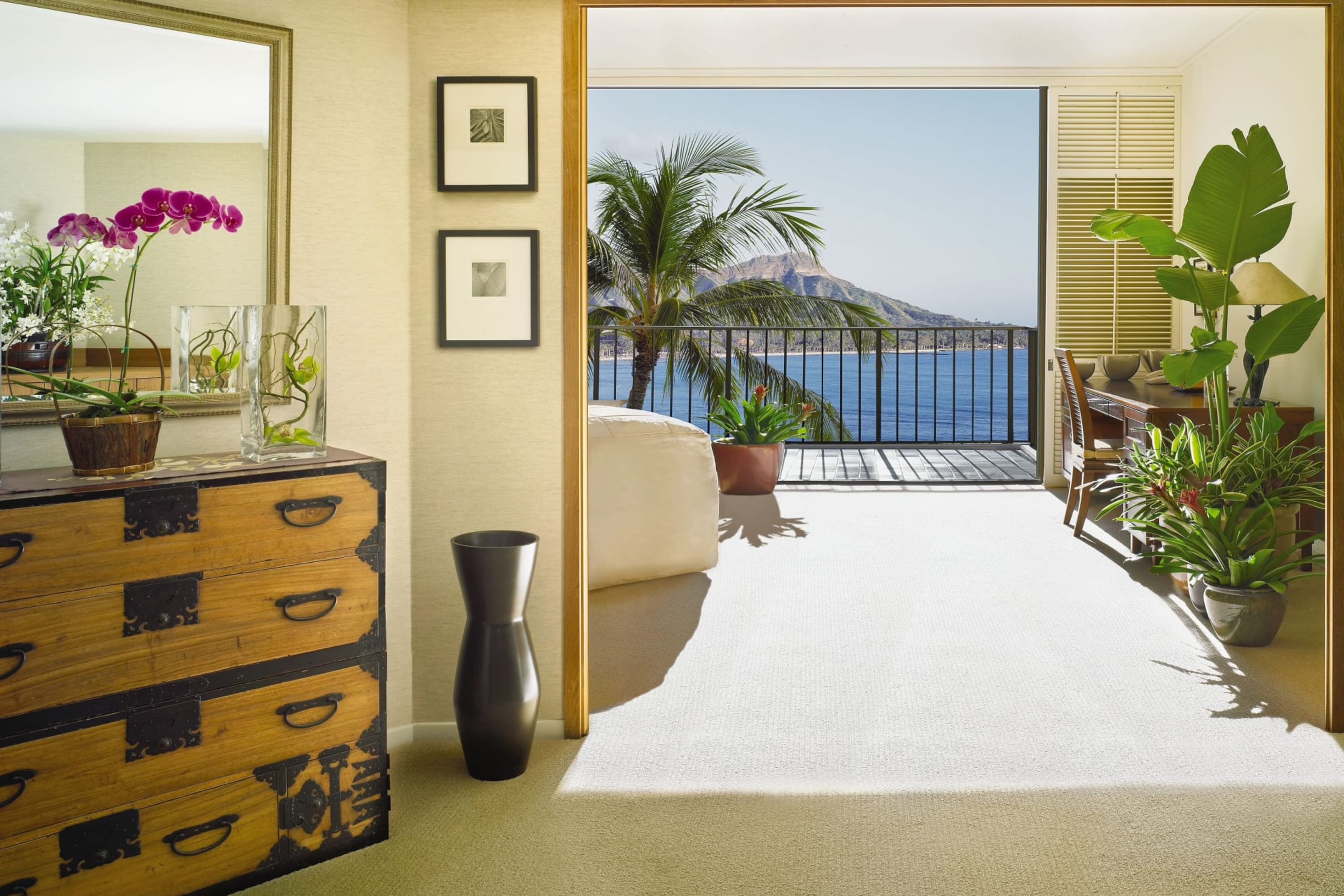 Spacious suite with vintage furniture, eclectic decor with a rustic spin, and a hallway leading to a living area and balcony with ocean views