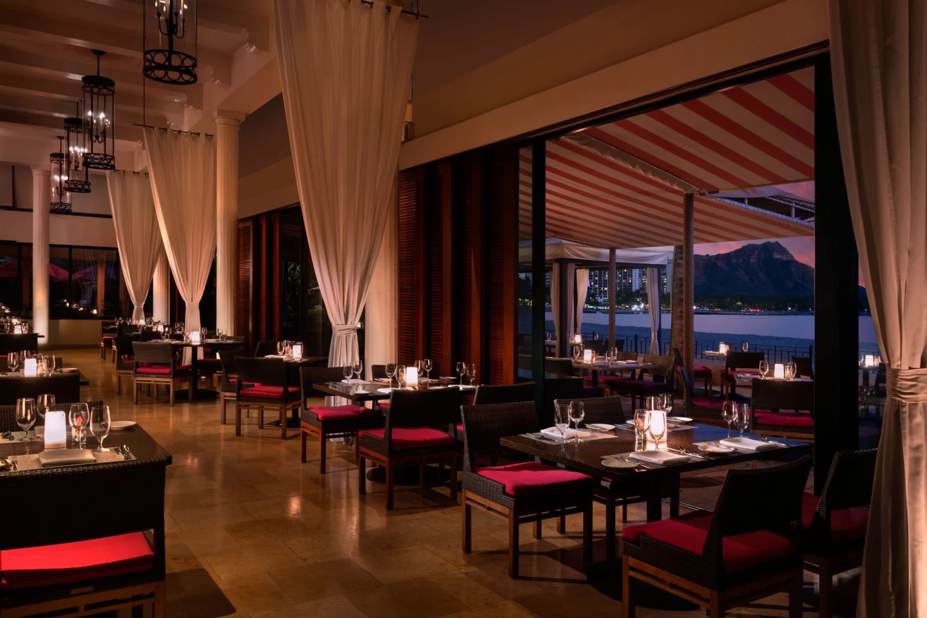Fine restaurant with elegant drapery, ocean views, classy table settings, moody lighting