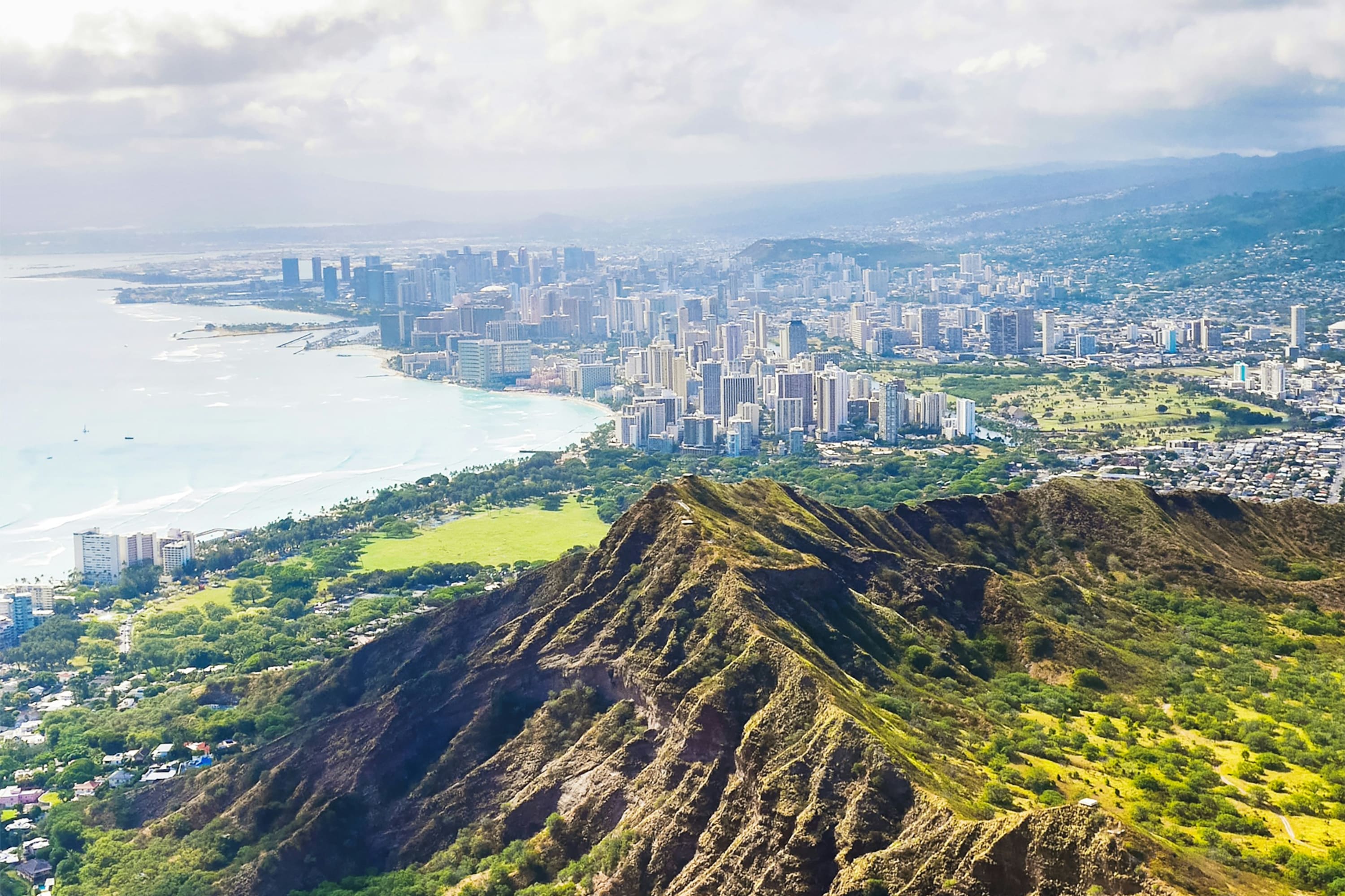Verdant mountain with Honolulu on the far side, the ocean to the west, and green hills to the east