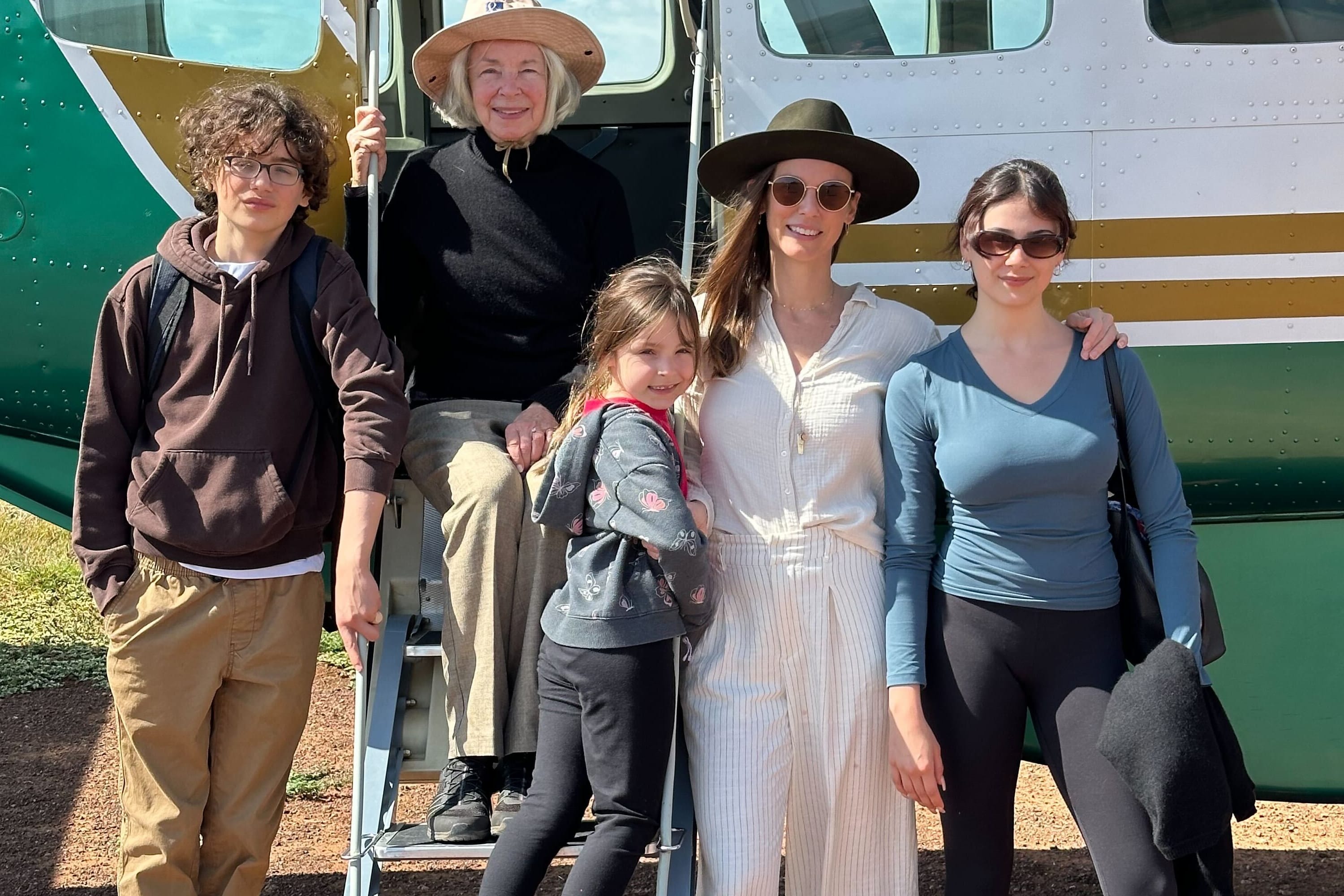 five people posing in front of an airplane