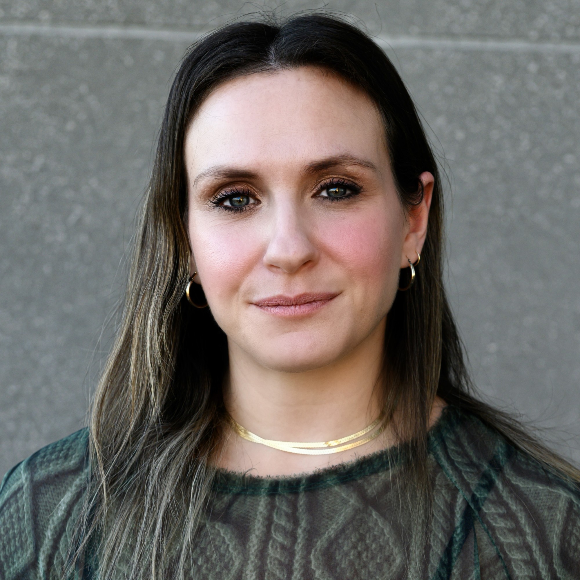 Travel Advisor Mindy Gabrielle wears a gray sweater in front of a gray wall