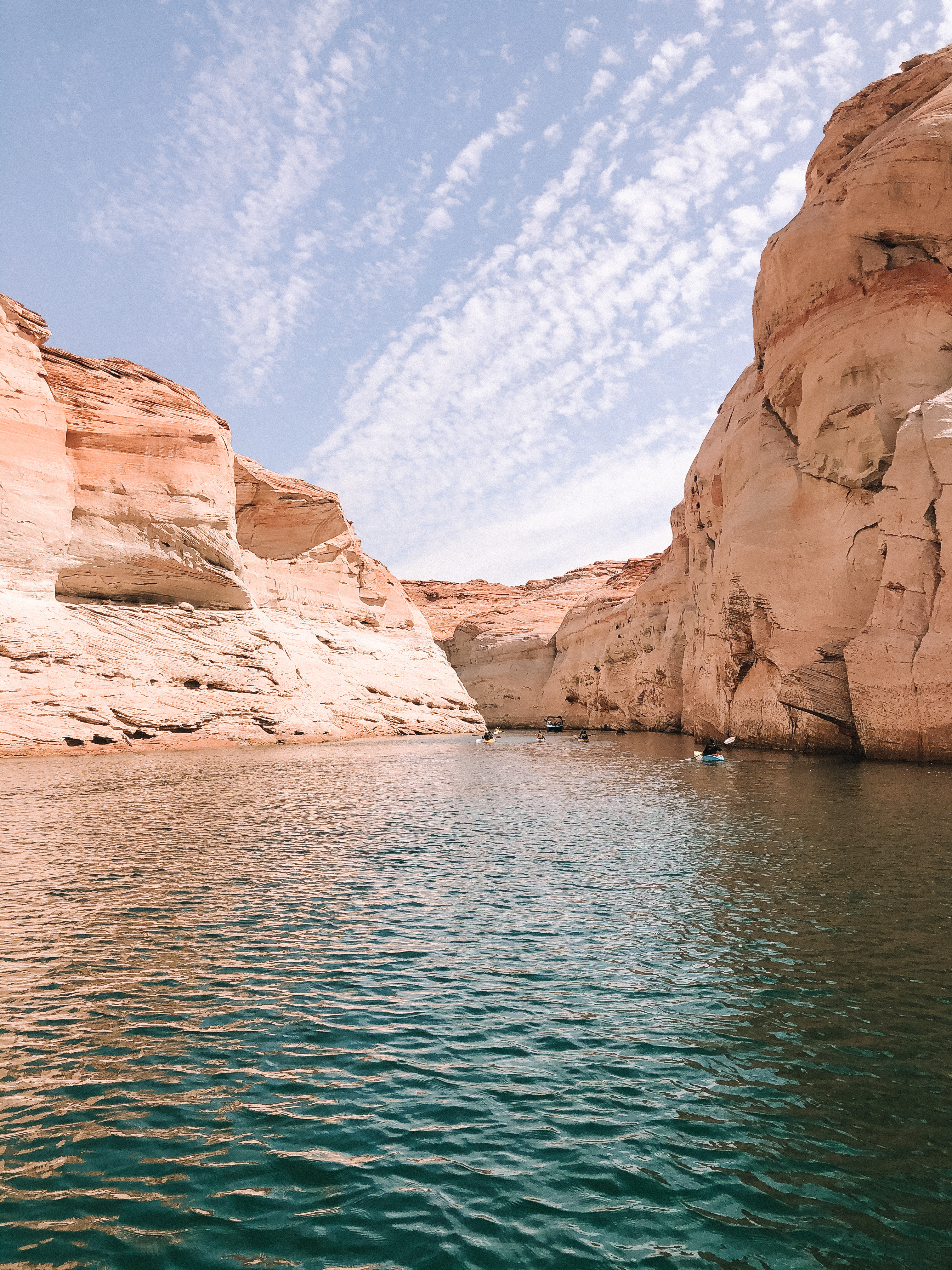 An ocean cove with large clay colored mountains during the day.