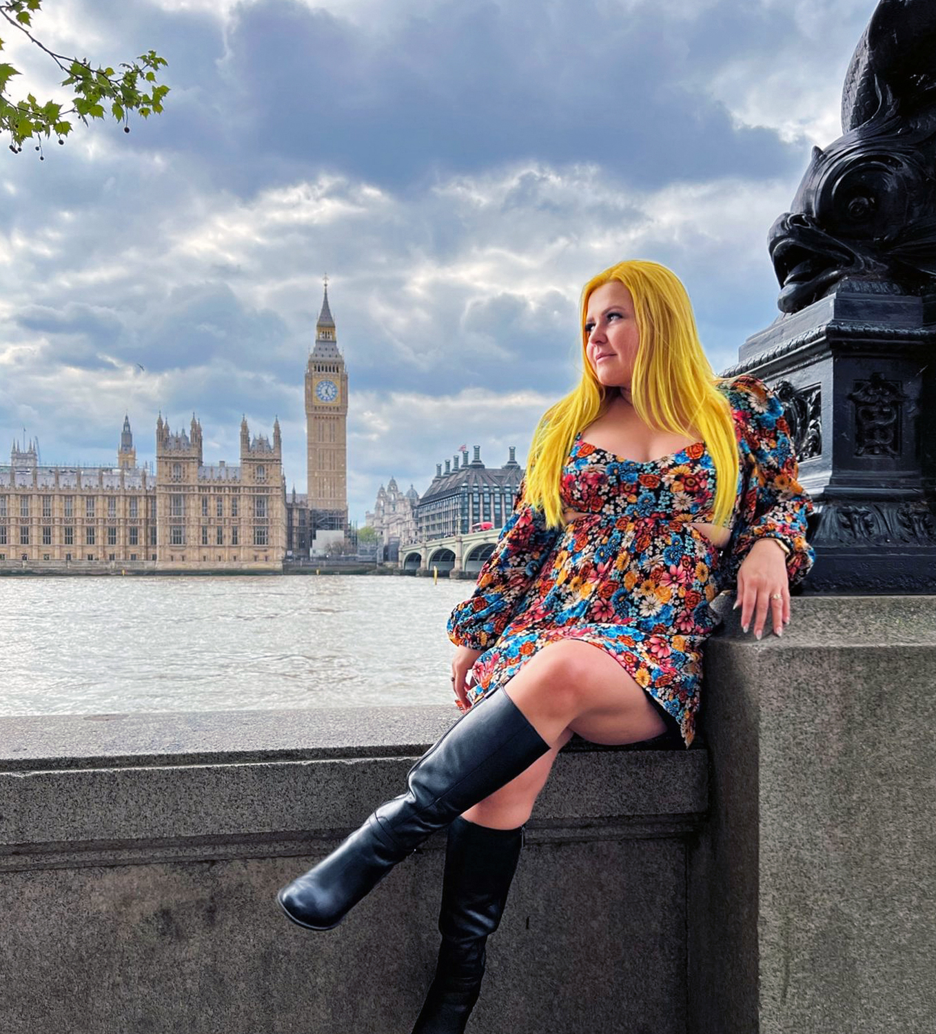 Natalia wearing a colorful dress and black boots posing along the Thames river with Big Ben in the background