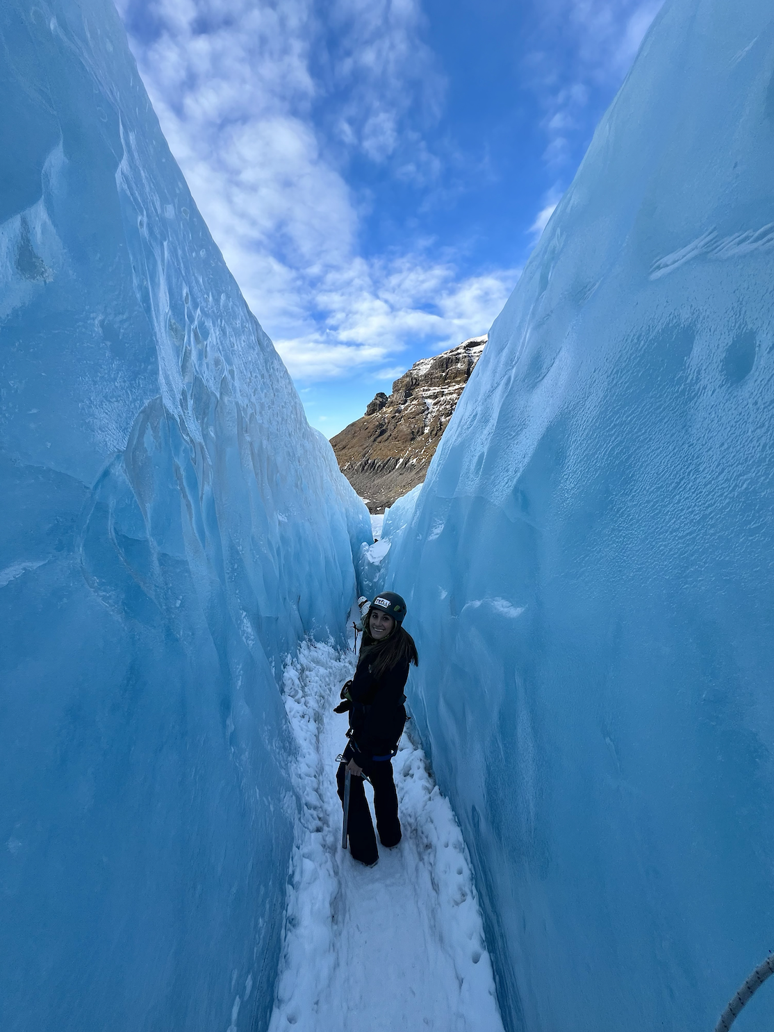 Photo of Sofia looking back at the camera from in between two large, blue glacier-like walls of ice
