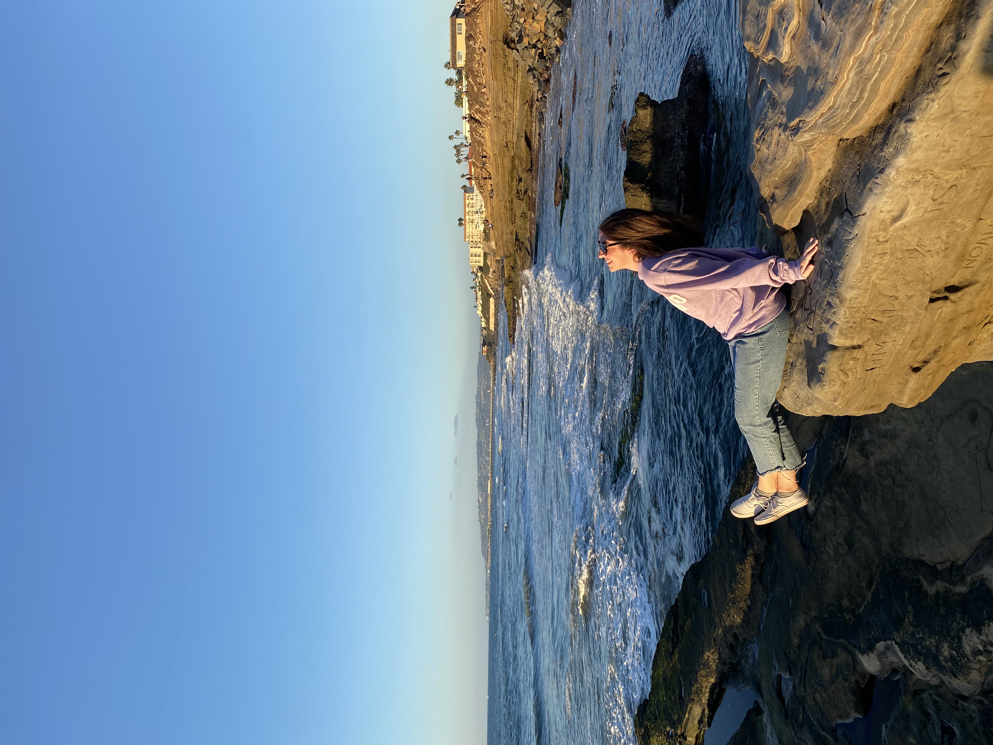 Advisor laying out on rock formations with the ocean in the distance.