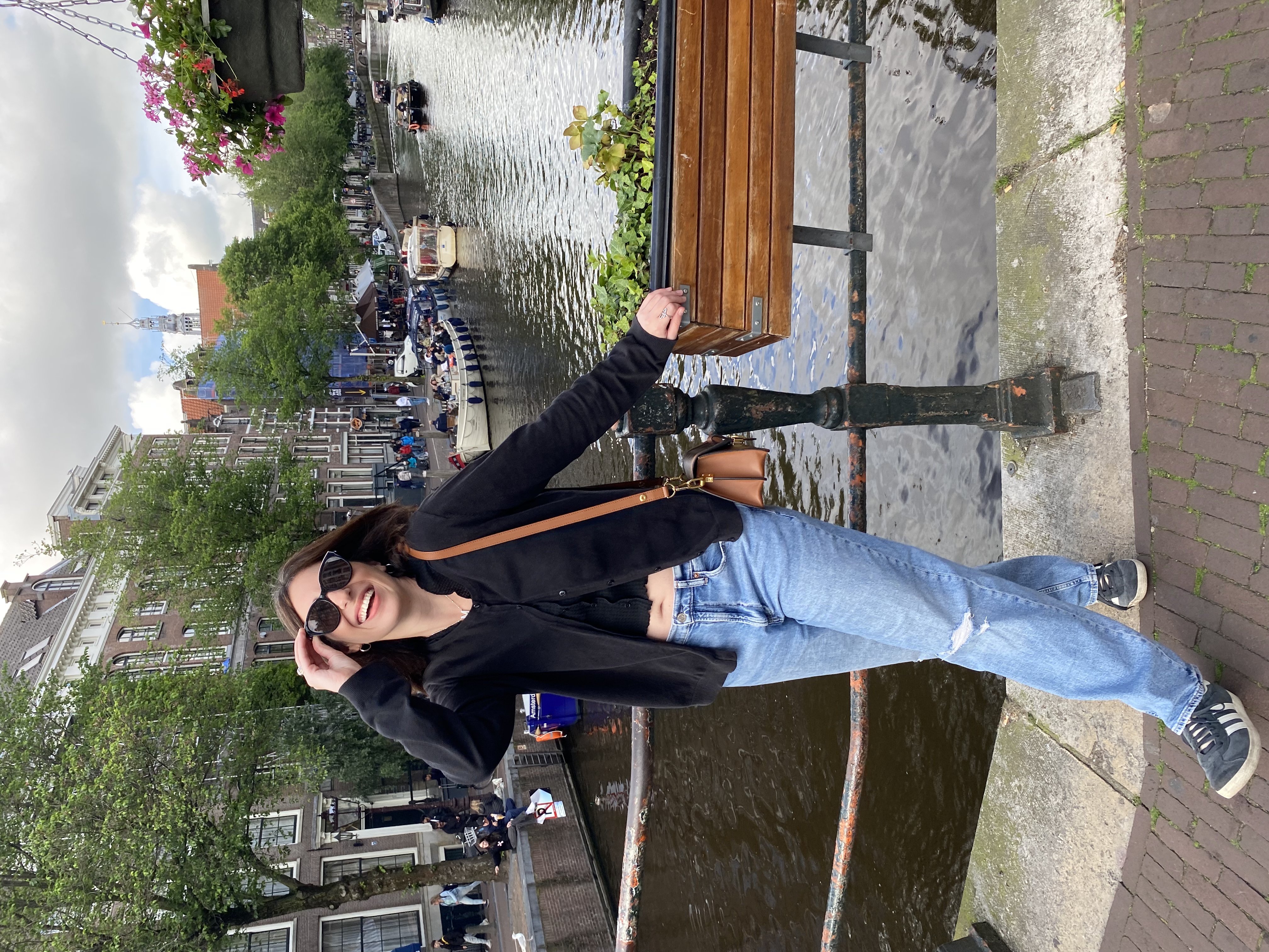 Advisor posing on a walkway over water with flower boxes on a sunny day.