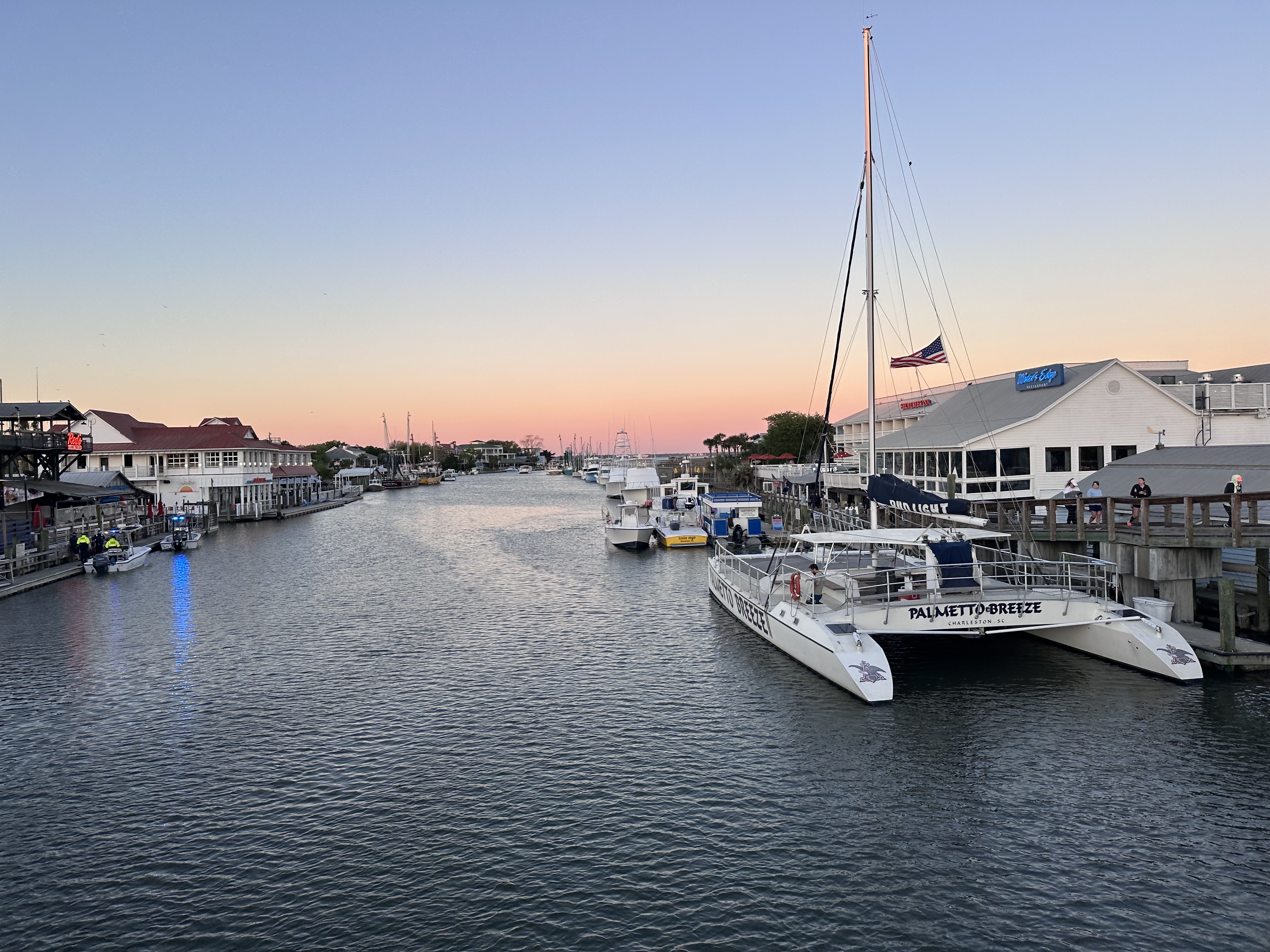 An image of a waterway with boats and houses along the shore at sunset.