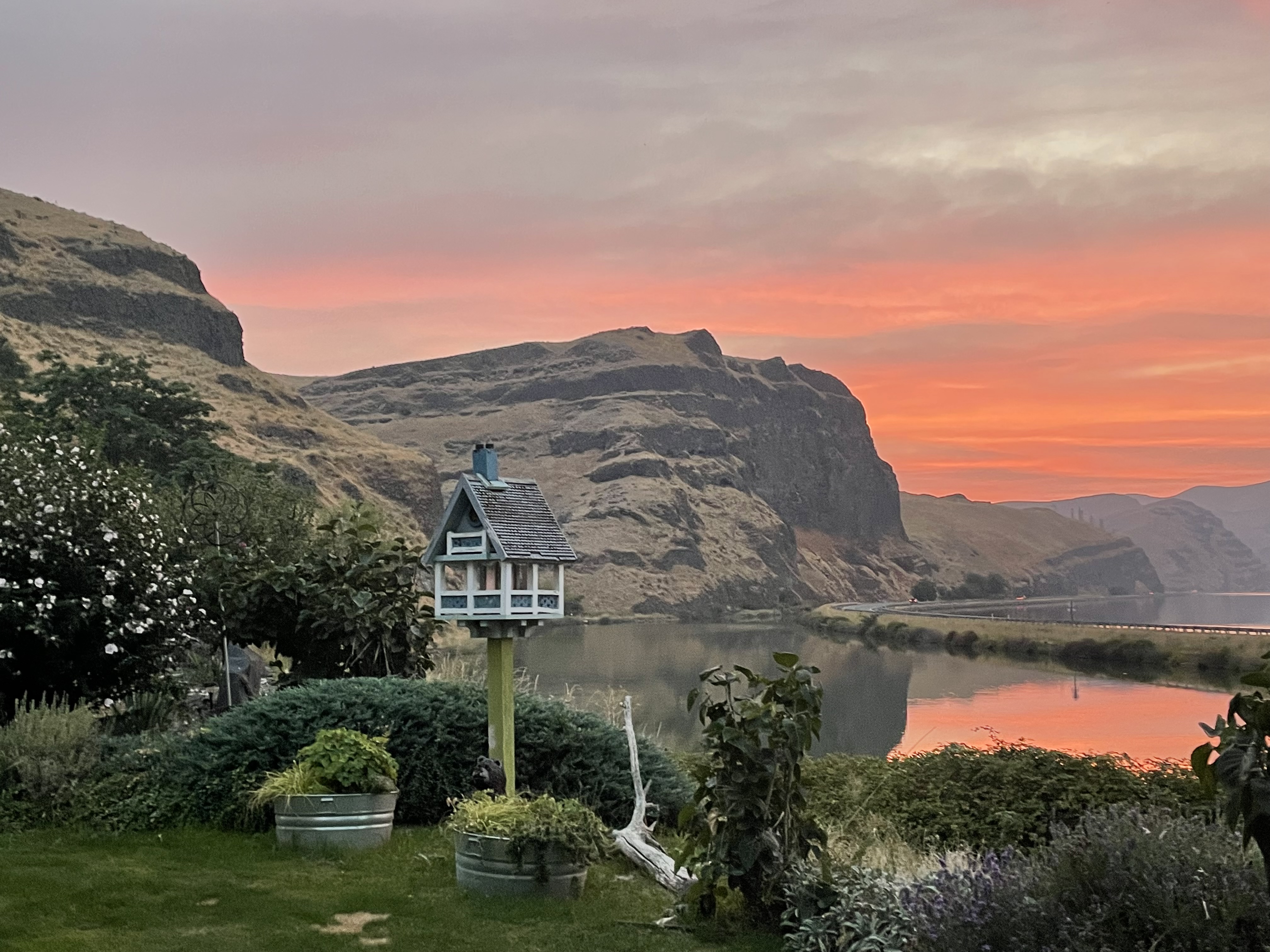An image of a body of water and rock formations with a bird house at sunset.