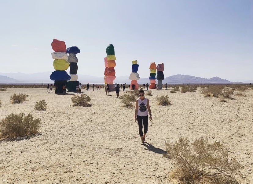 An image of the dessert with colorful art statues in the distance on sunny day.