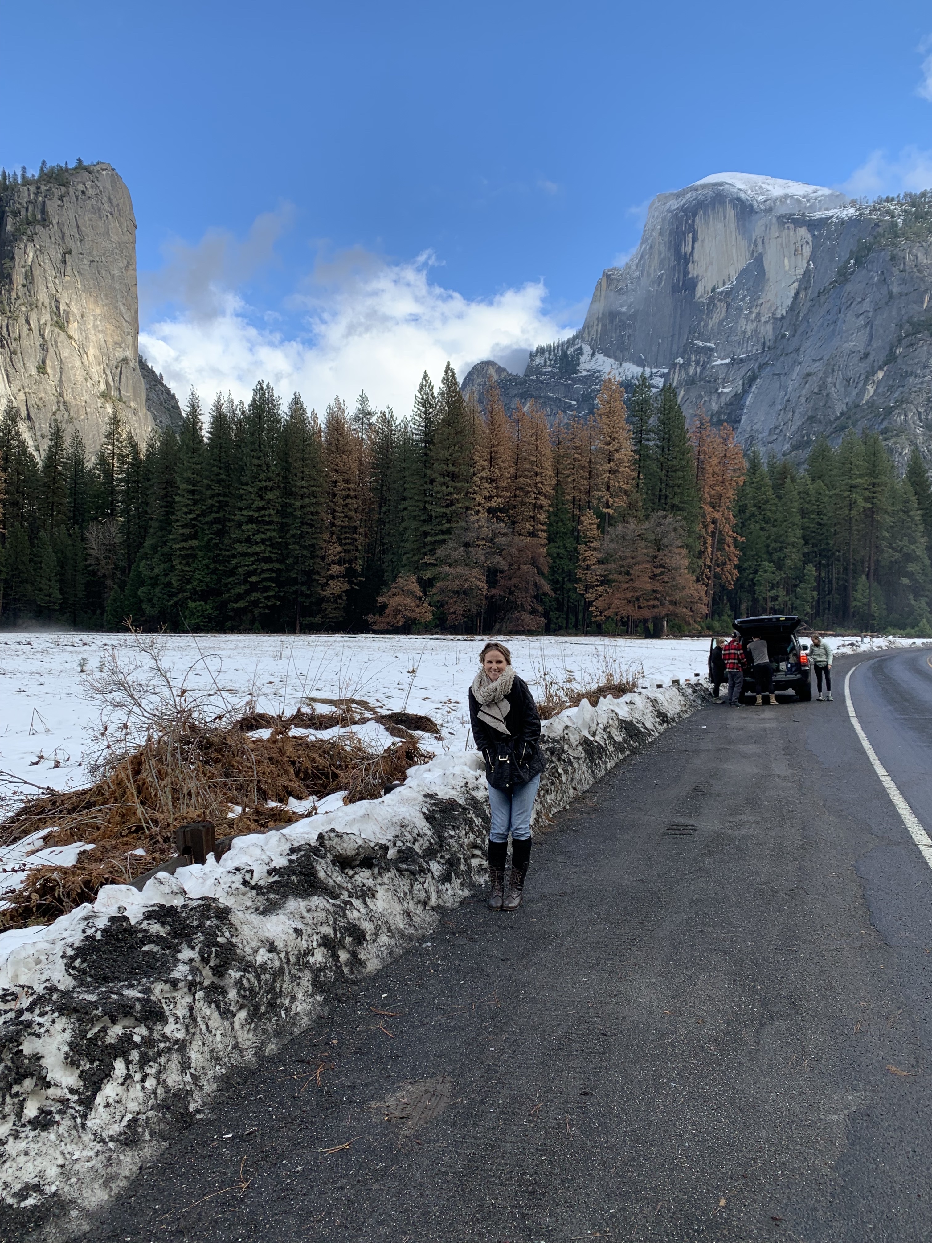 Advisor posing in snowy region with mountains and trees in the distance.