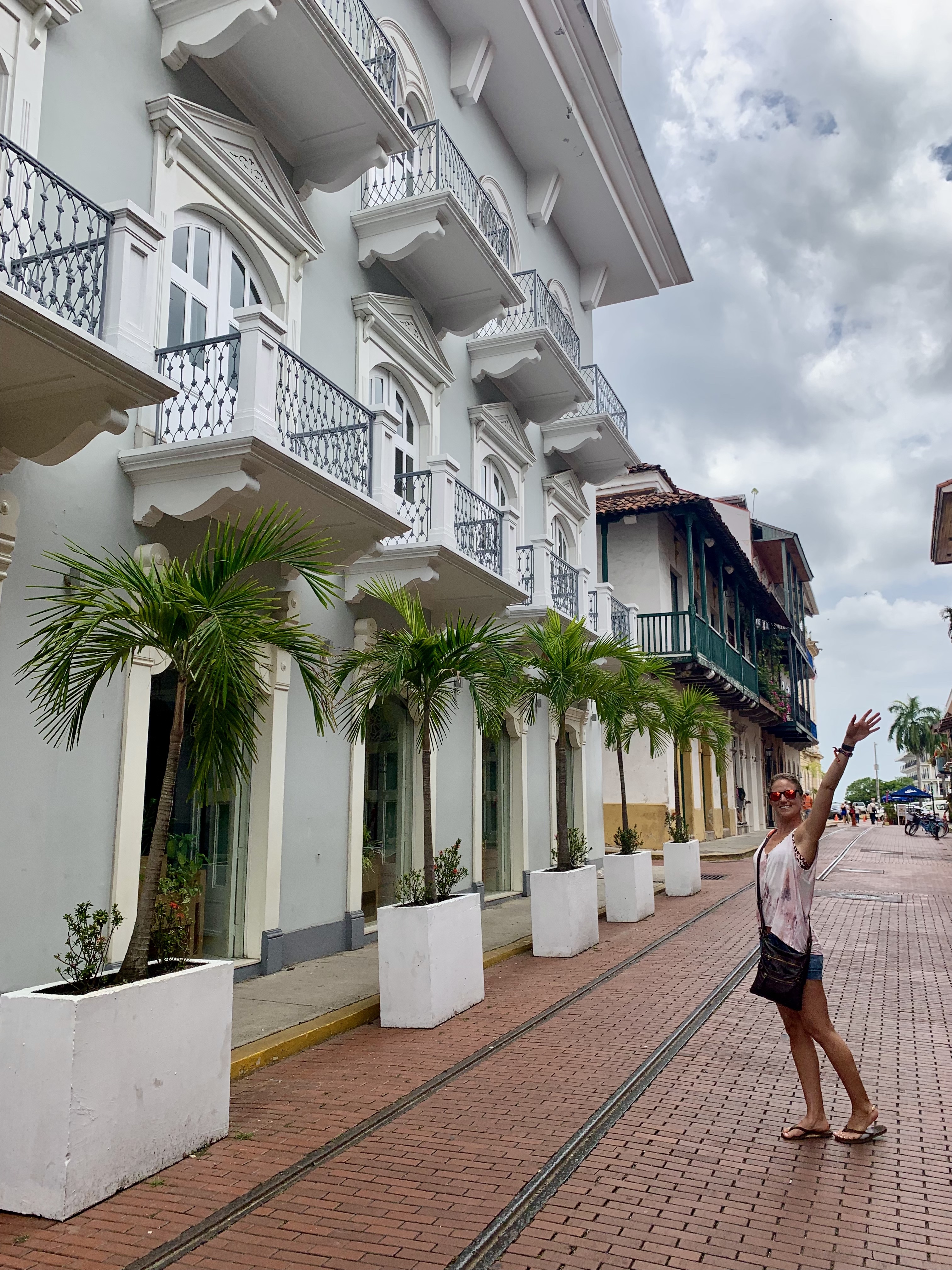 Advisor posing for a photo outside of a large white hotel with foliage on cloudy day.
