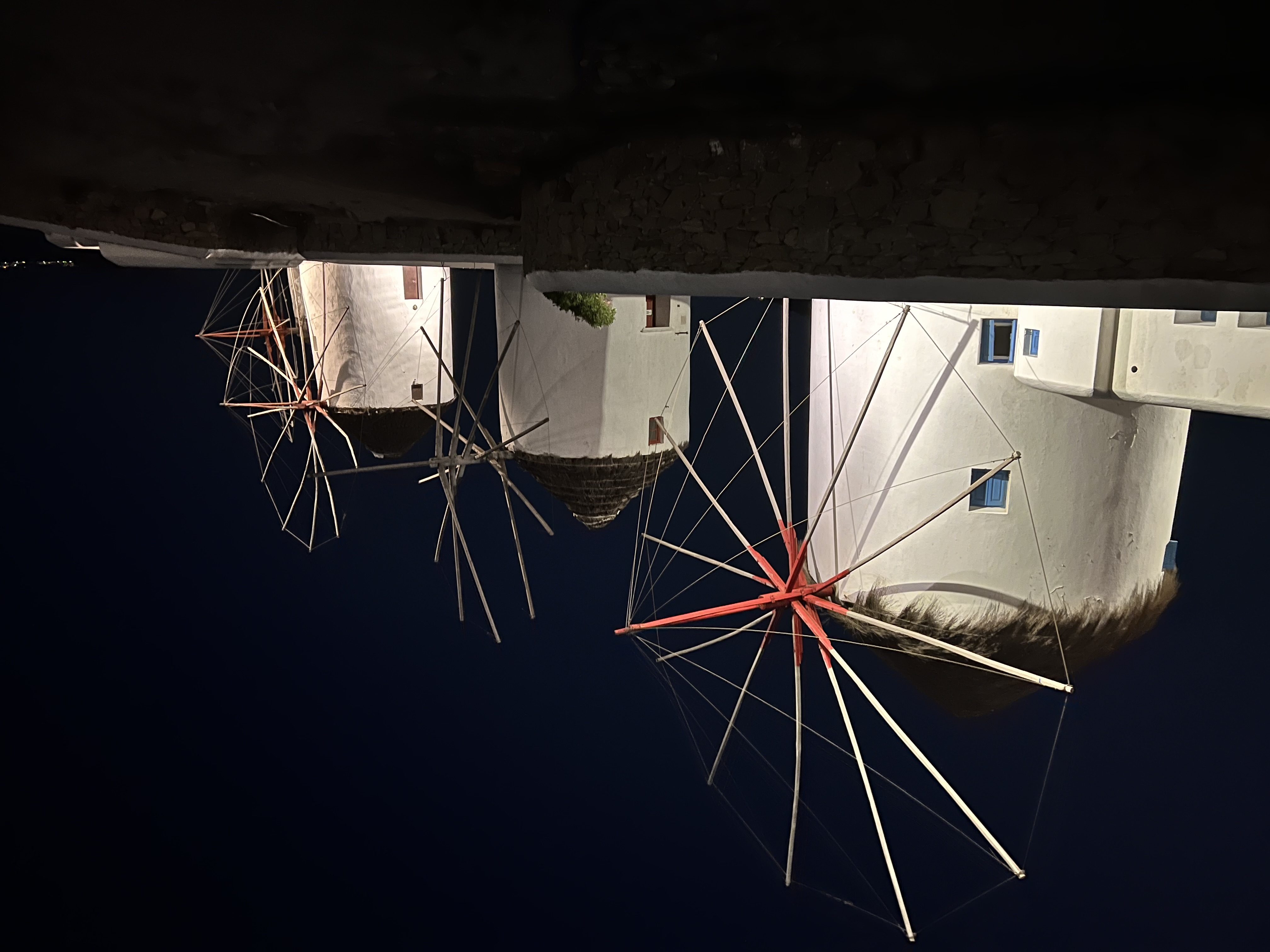 View of three white cylindrical windmills lit up at night