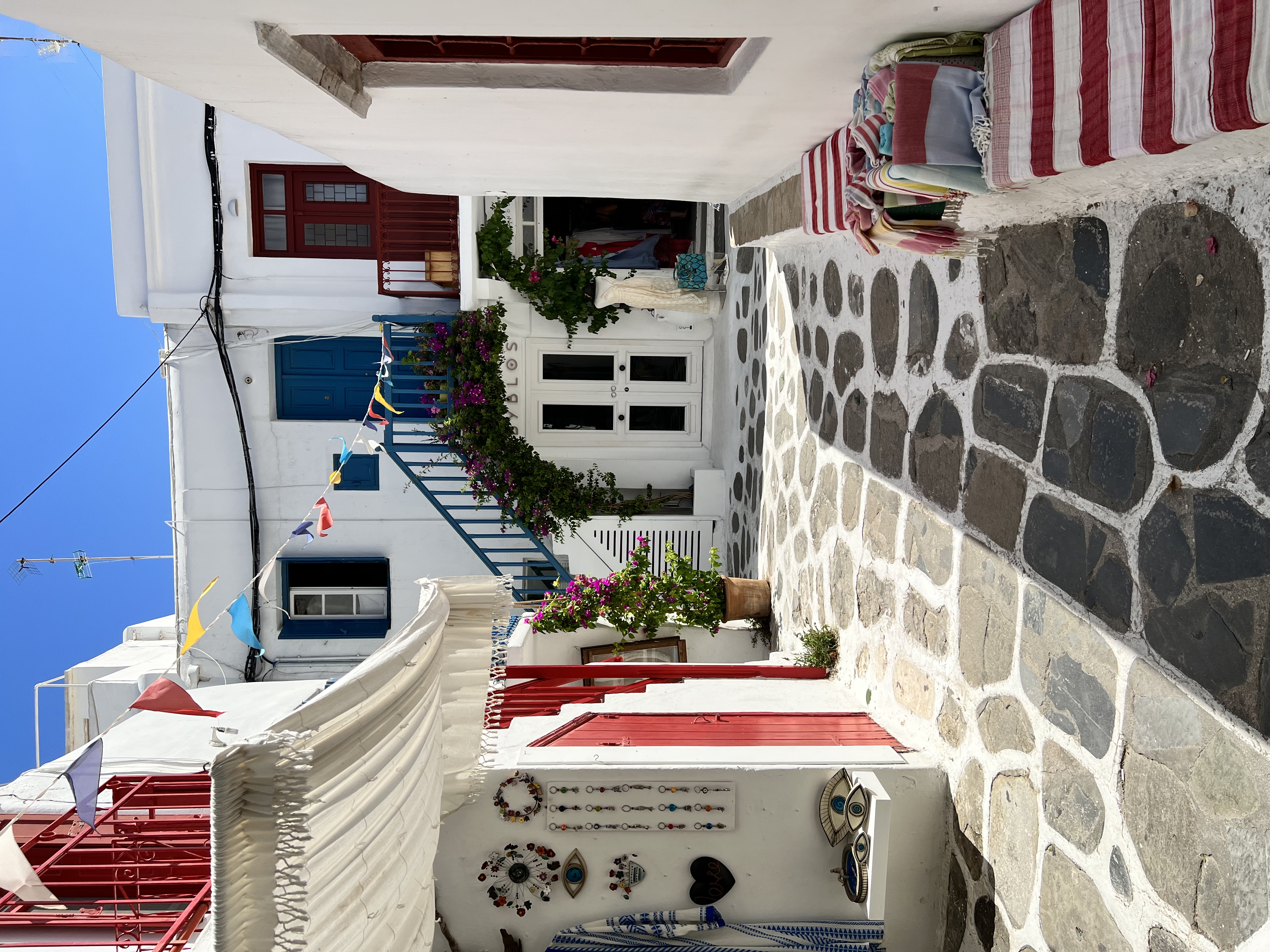 Pretty view of a stone path between small white buildings with red doors on a sunny day