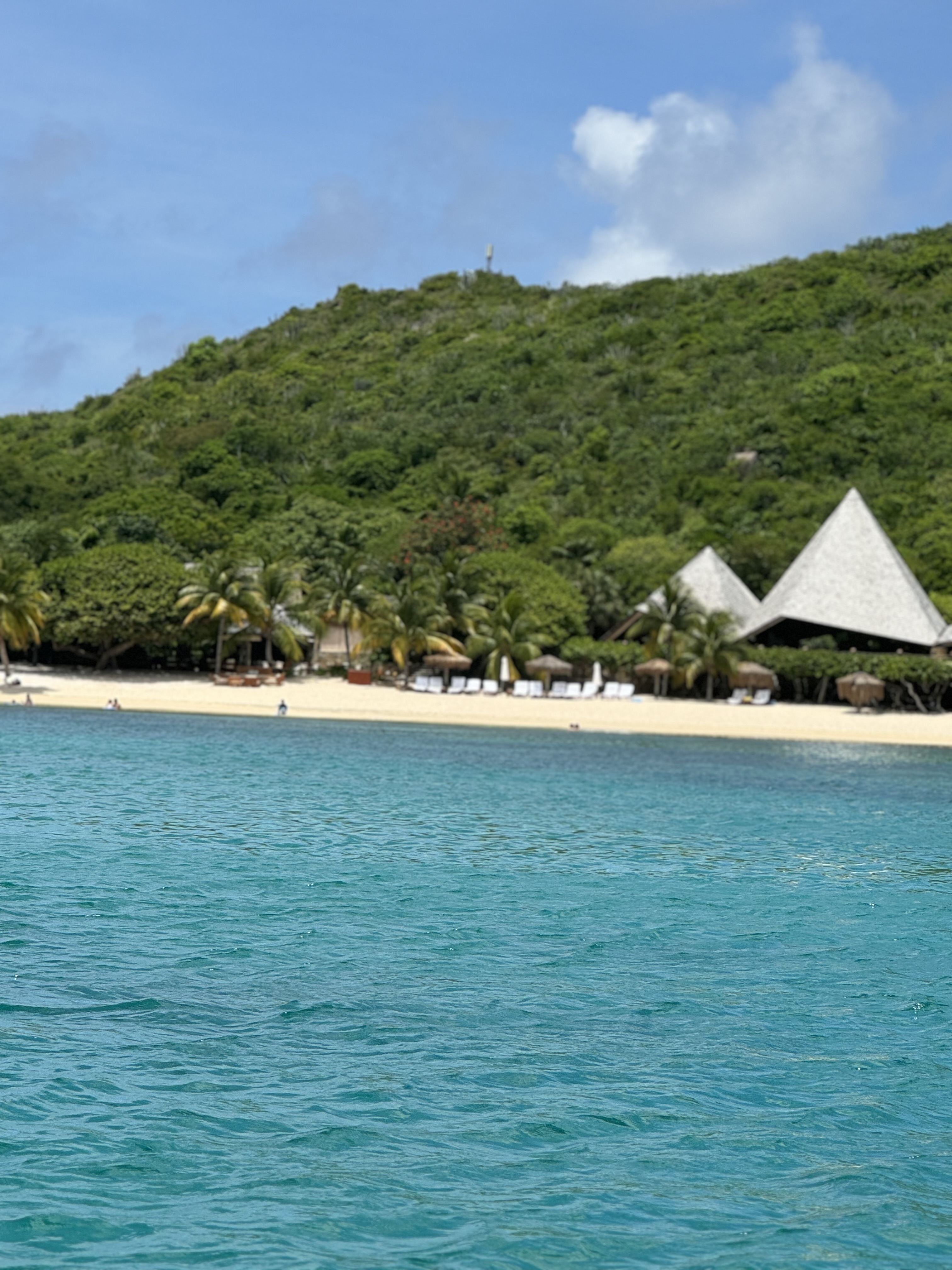 Beautiful view of a turquoise sea and beyond a clean white sand beach with white tents