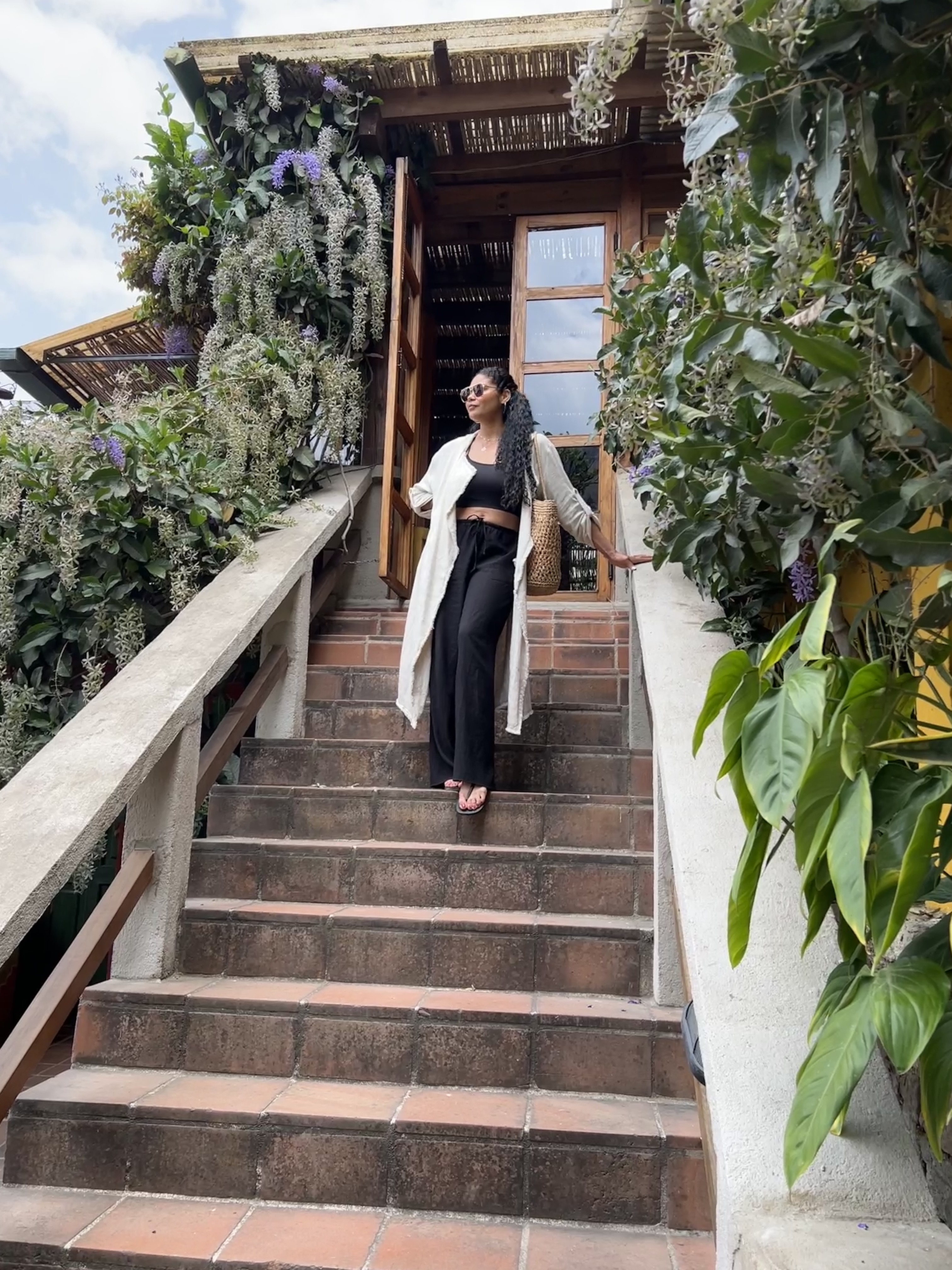 Advisor walking down a staircase in a black outfit with foliage on a sunny day.