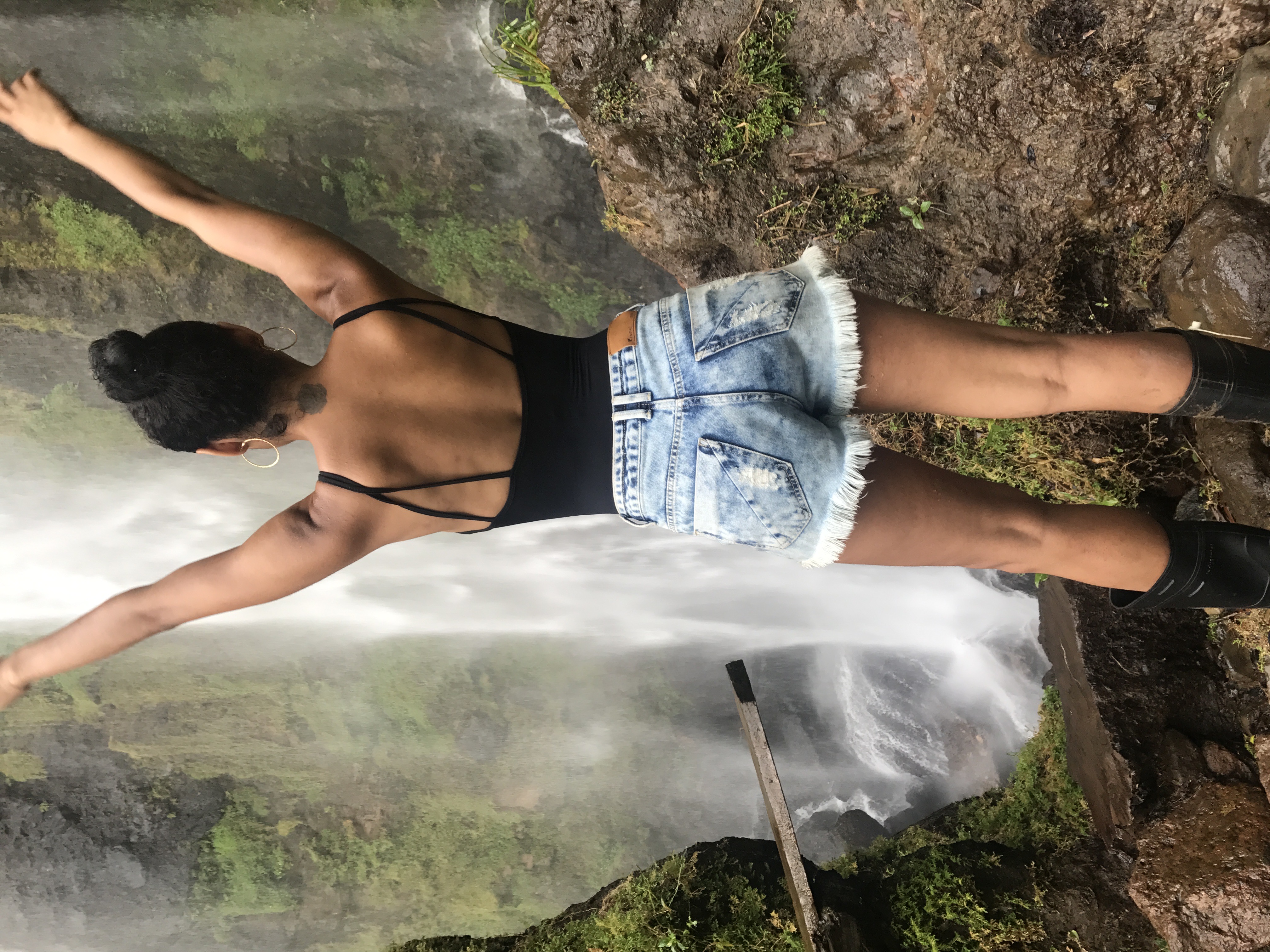 Advisor posing for an image in front of a waterfall in a tropical region.
