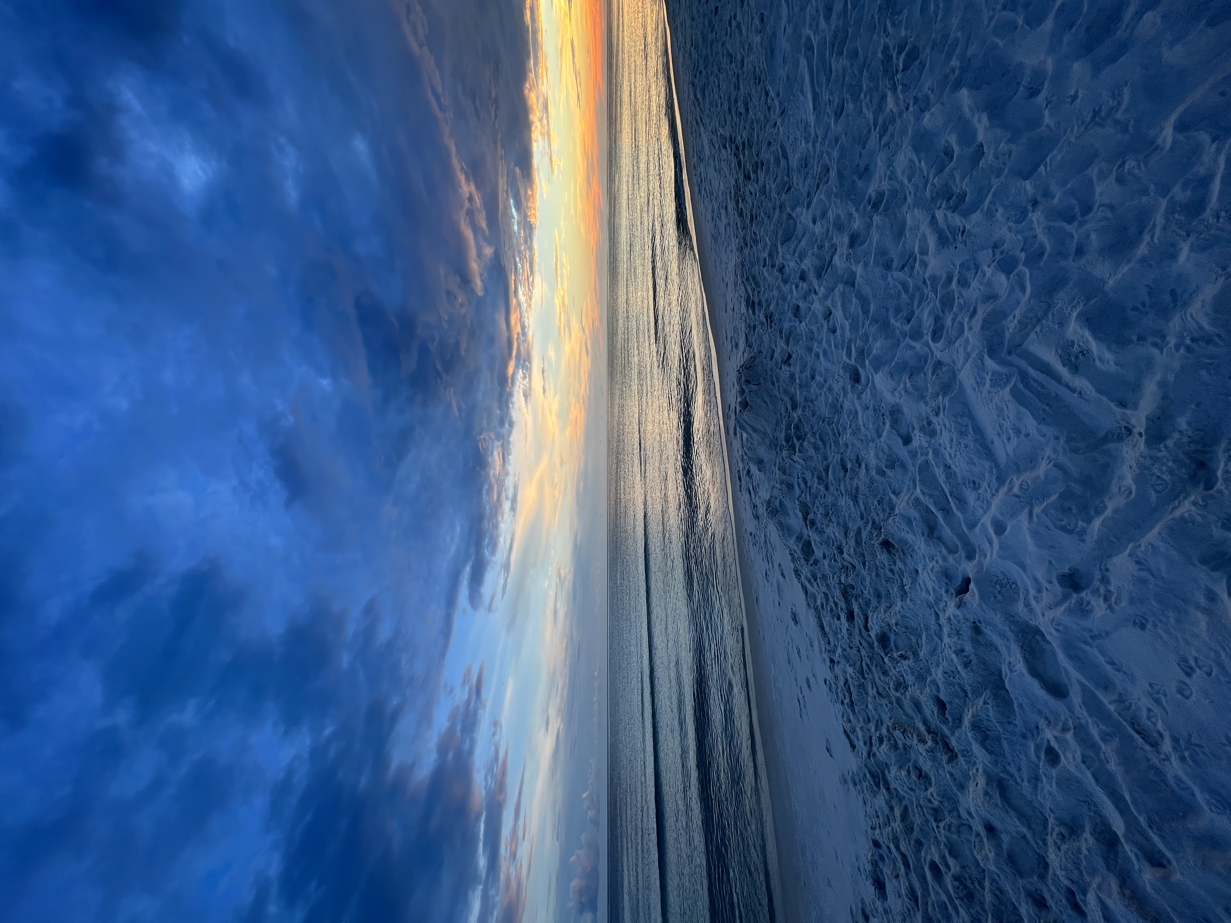A view of a beautiful blue sunset on the beach with a golden sky.