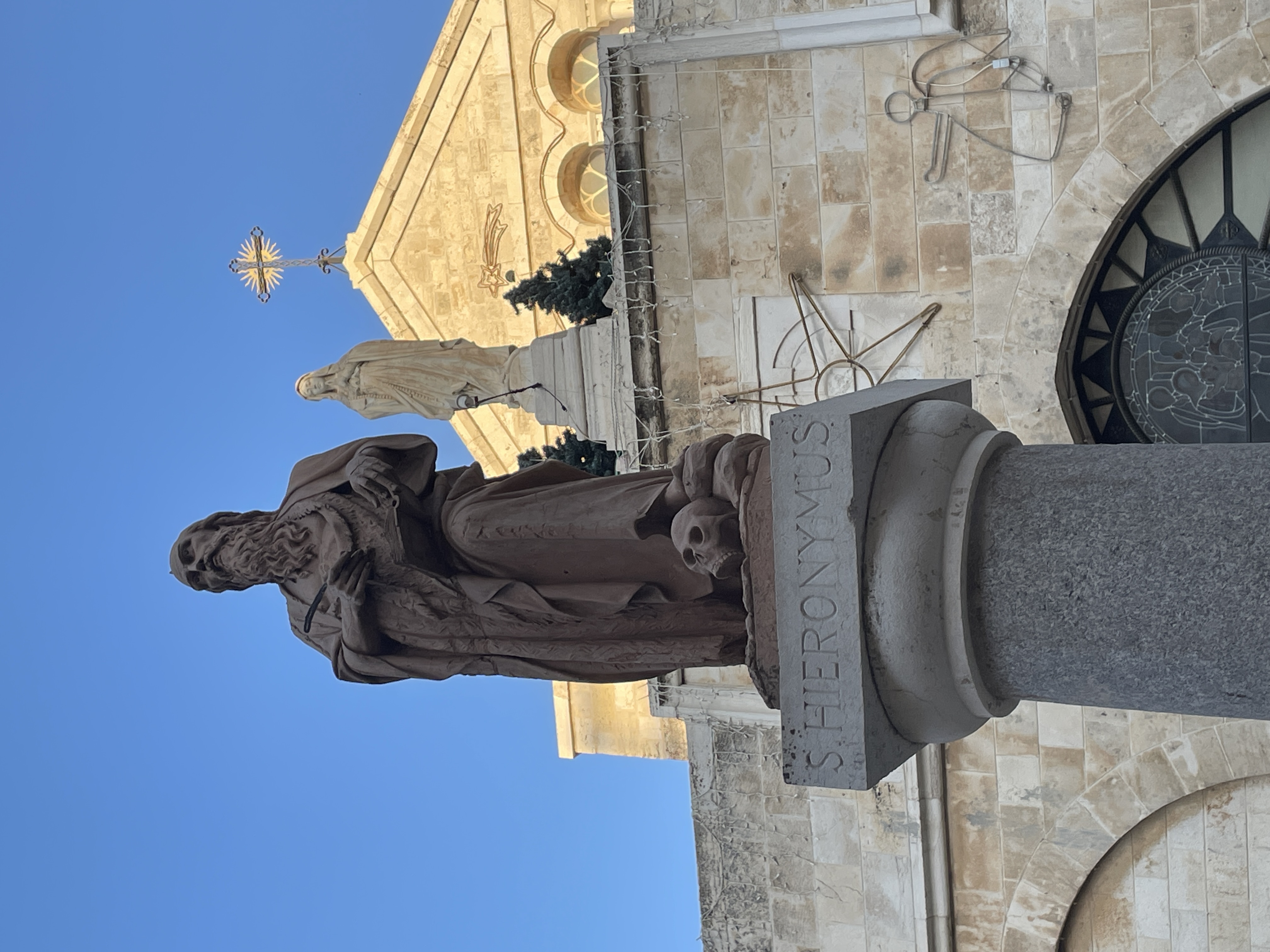 A statue with buildings in the distance on a sunny day.