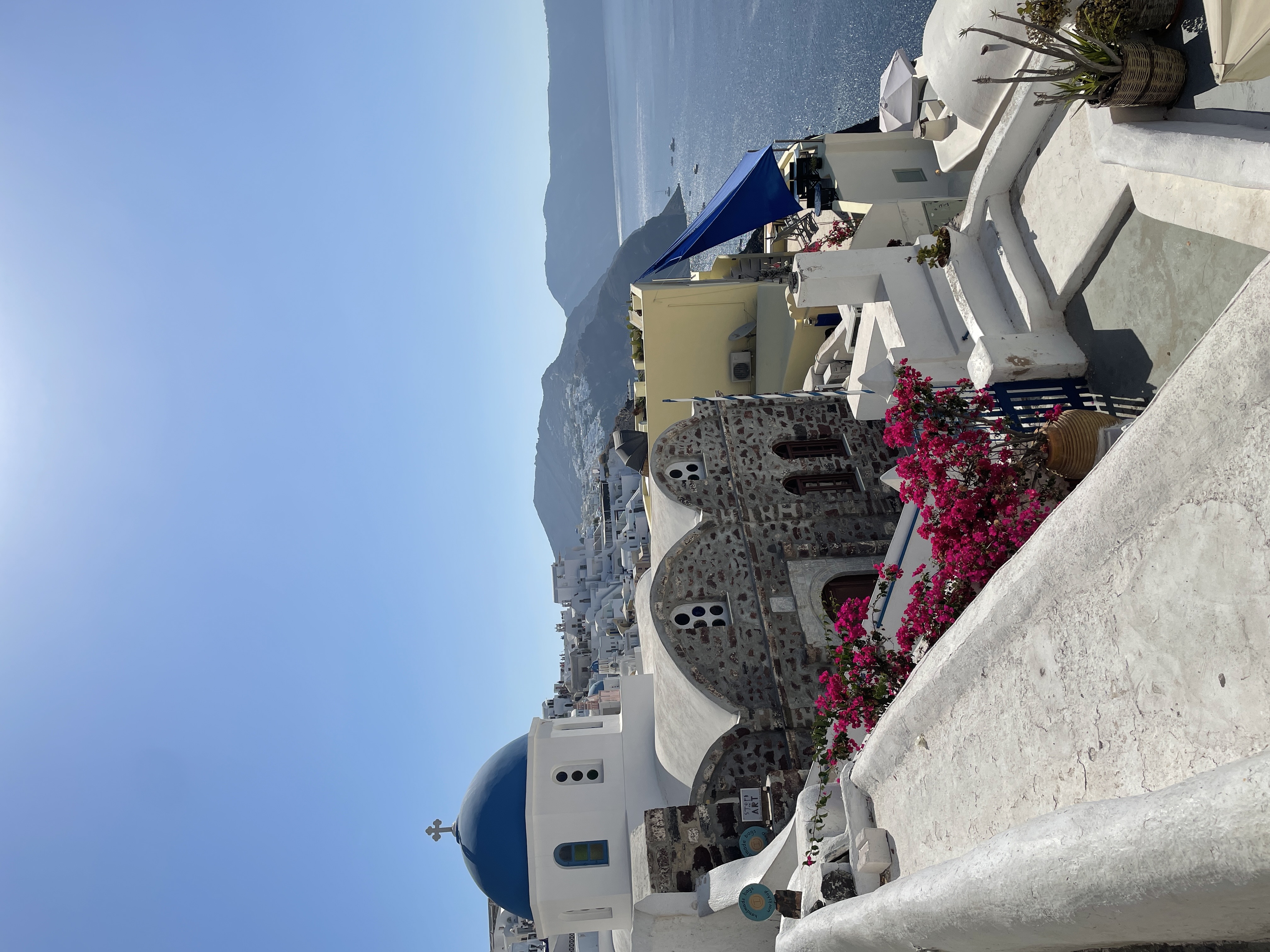 A view of a mountain side with a town and the ocean in the distance.