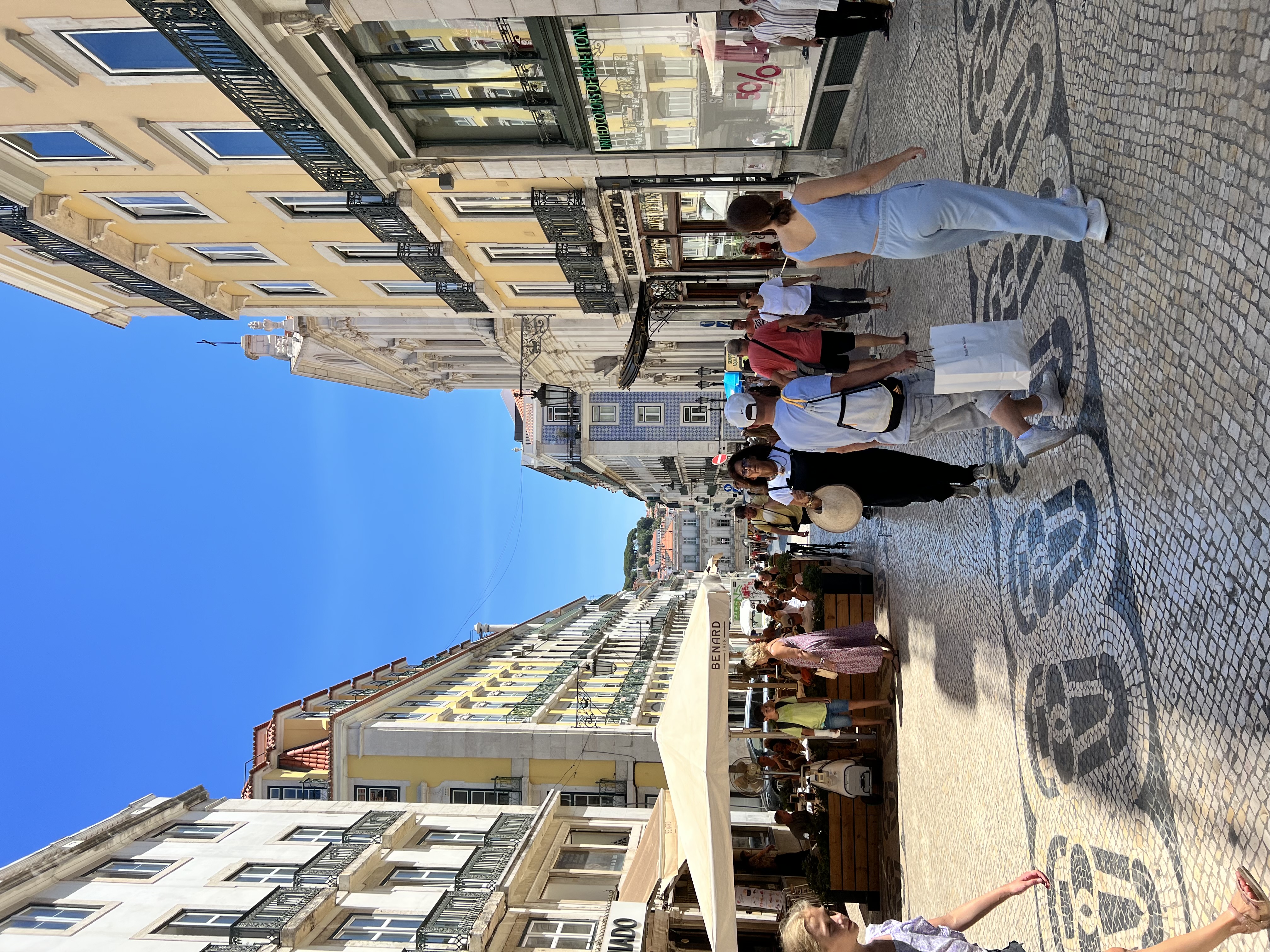 View of a tiled city street with many pedestrians on a sunny day