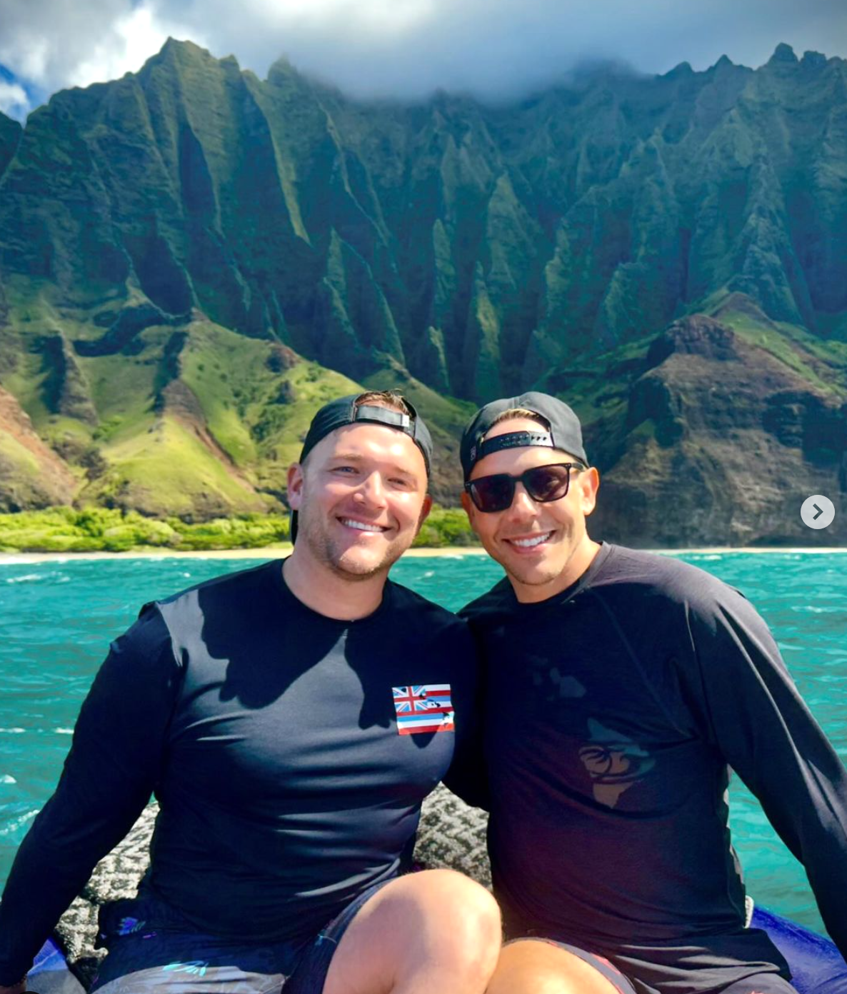 Andrew and a man in backwards baseball caps smiling for a photo on a bright blue lake with beautiful mountain background