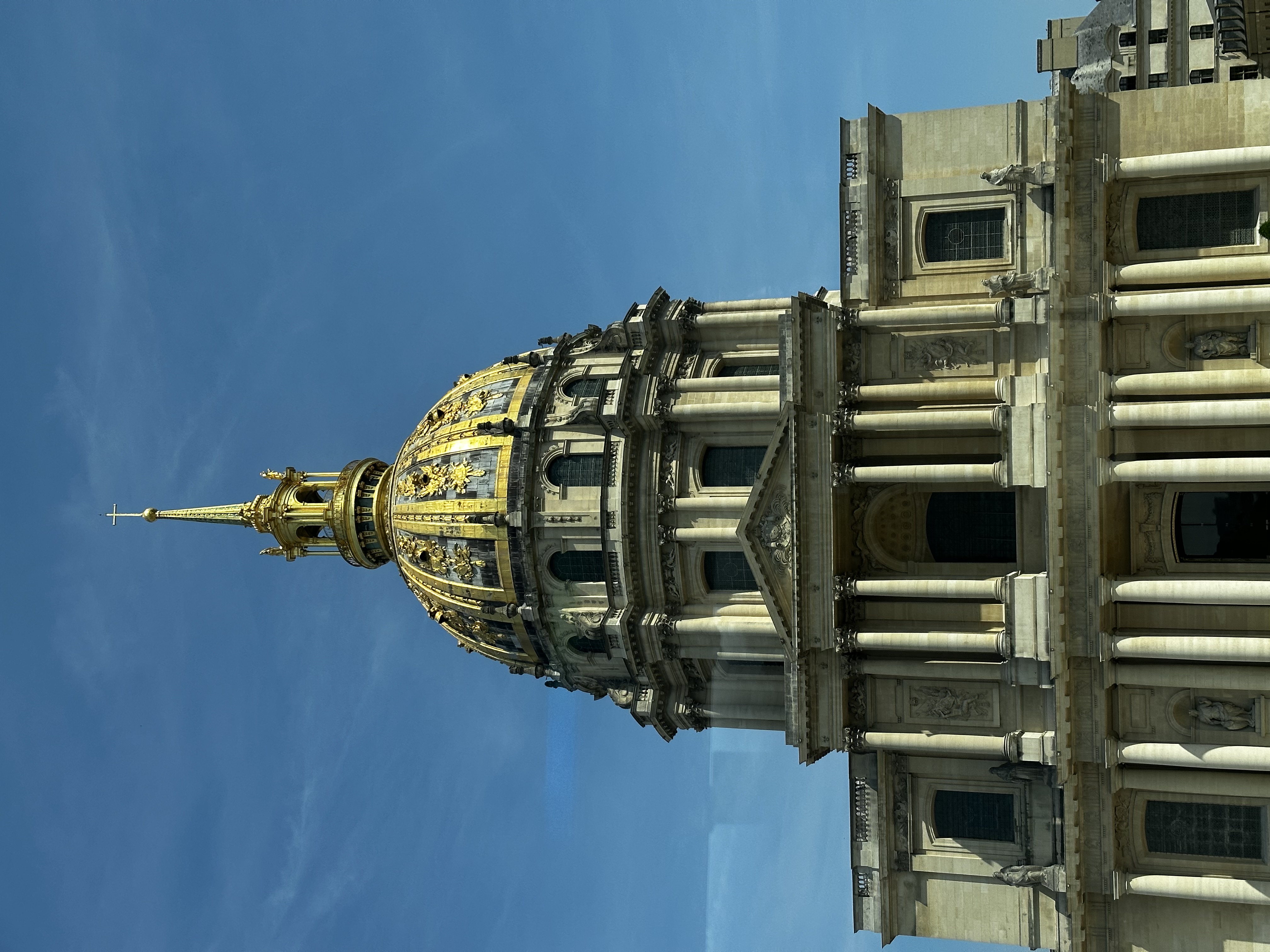 View of a domed building with columns and a spire on top on a clear day