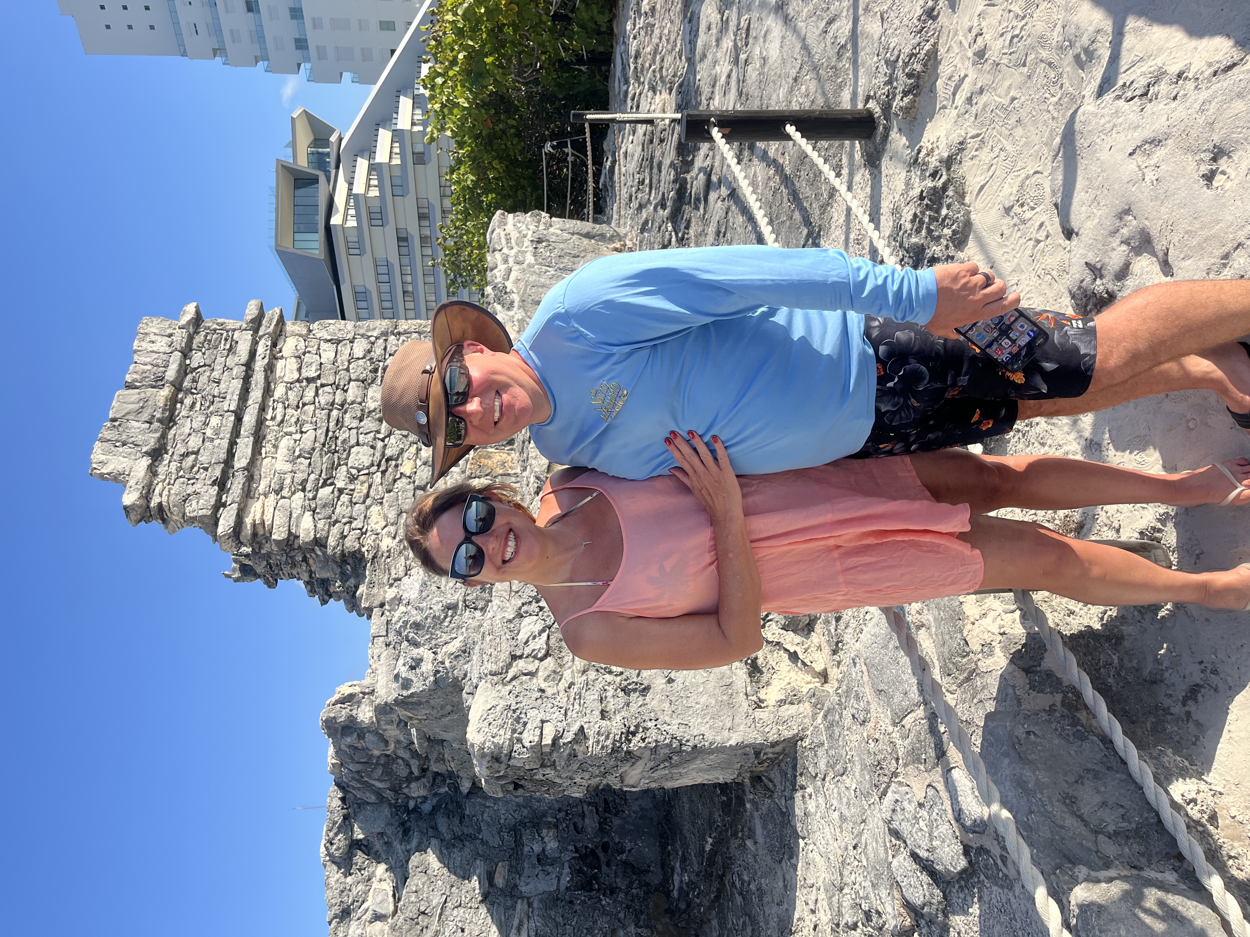 Couple standing in front of ruins on a sunny day.