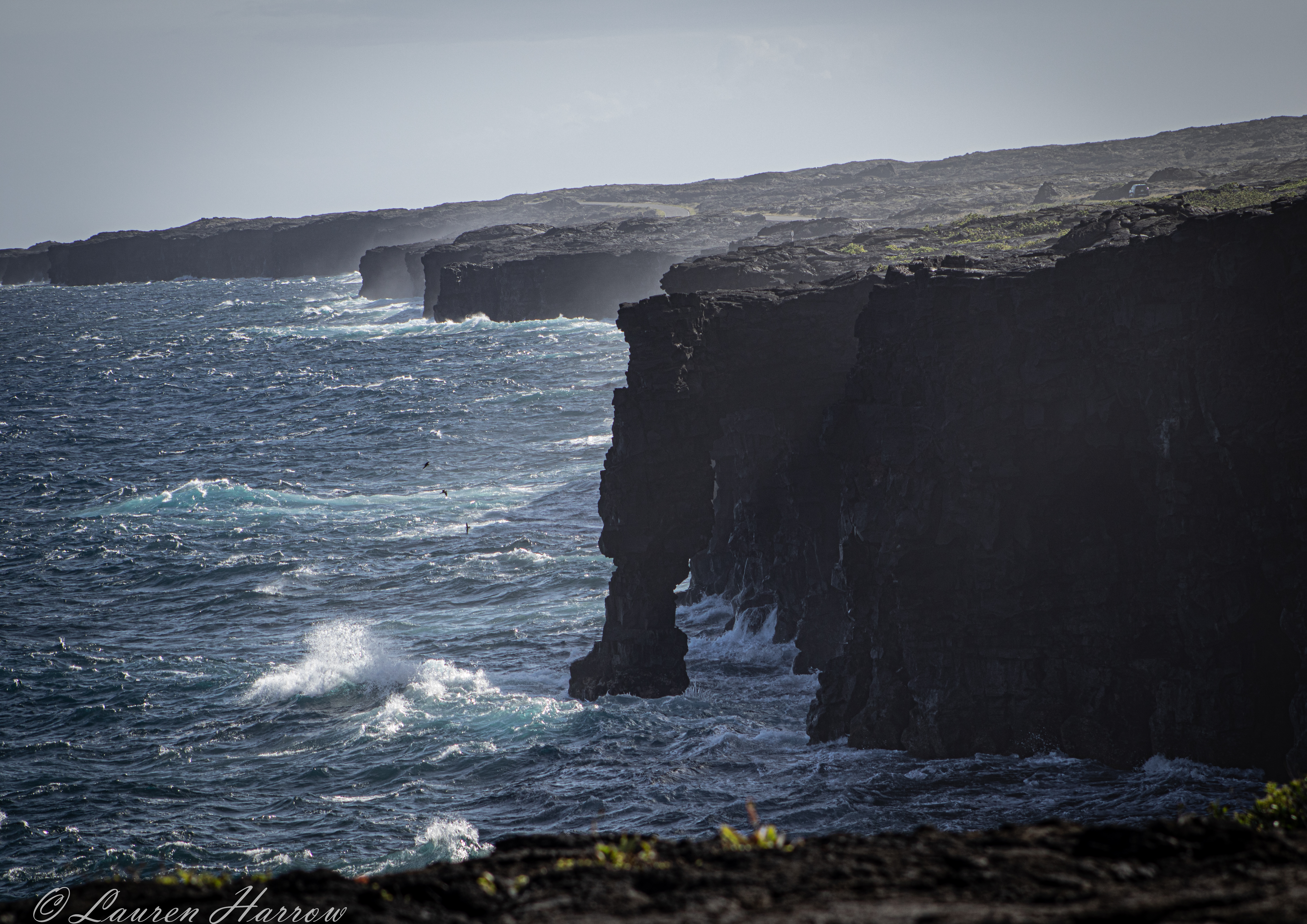 A view of lapping waves against a craggy coast on a clear, sunny day.
