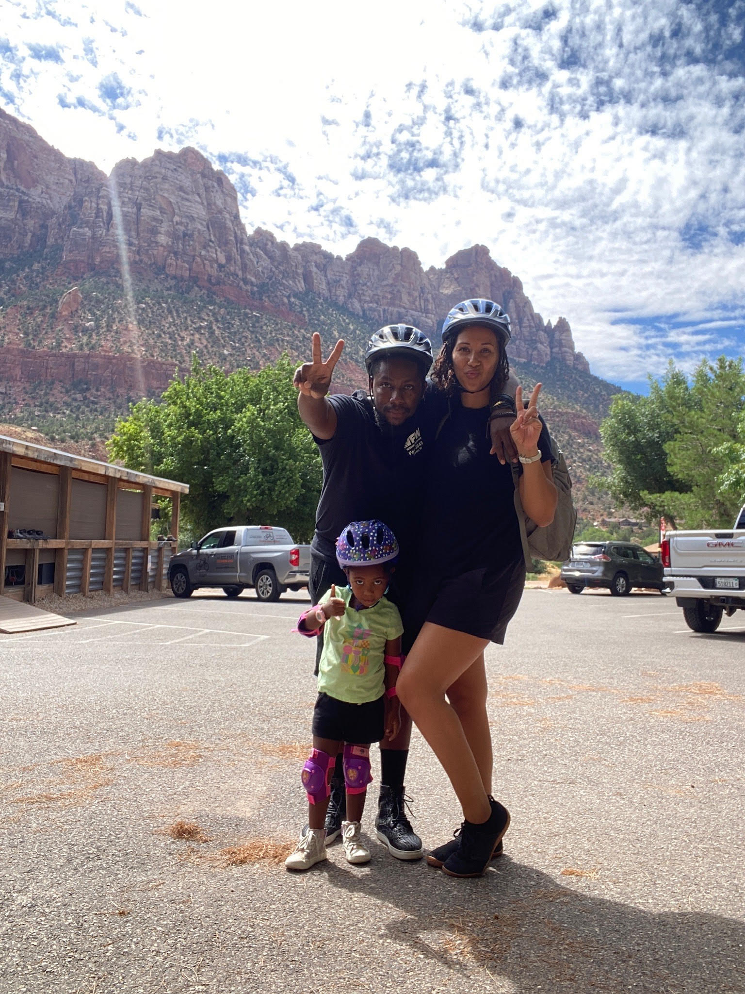 Advisor posing with child and husband at the base of a mountain range on a sunny day.