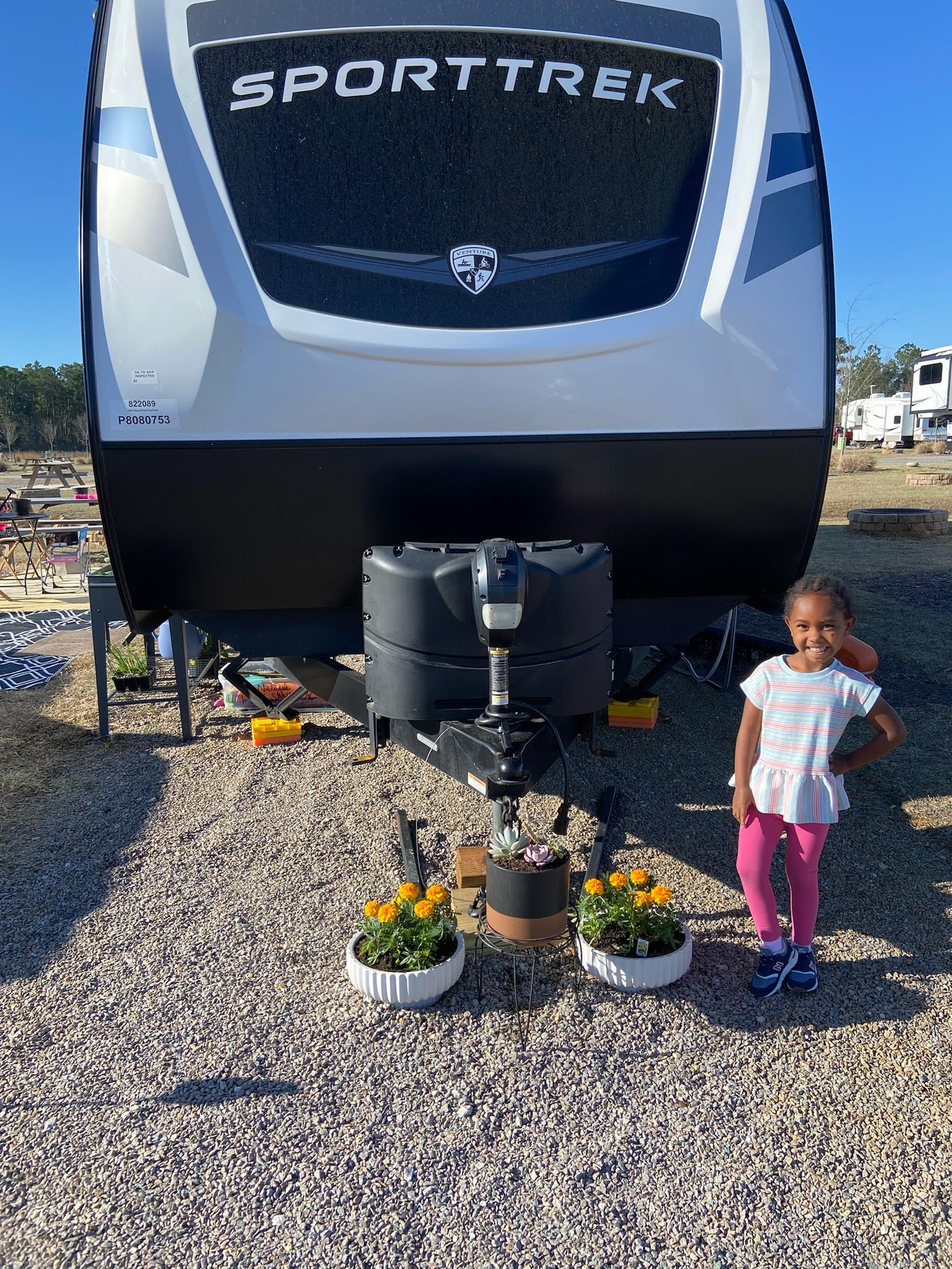 Child posing in front of an RV on a sunny day.