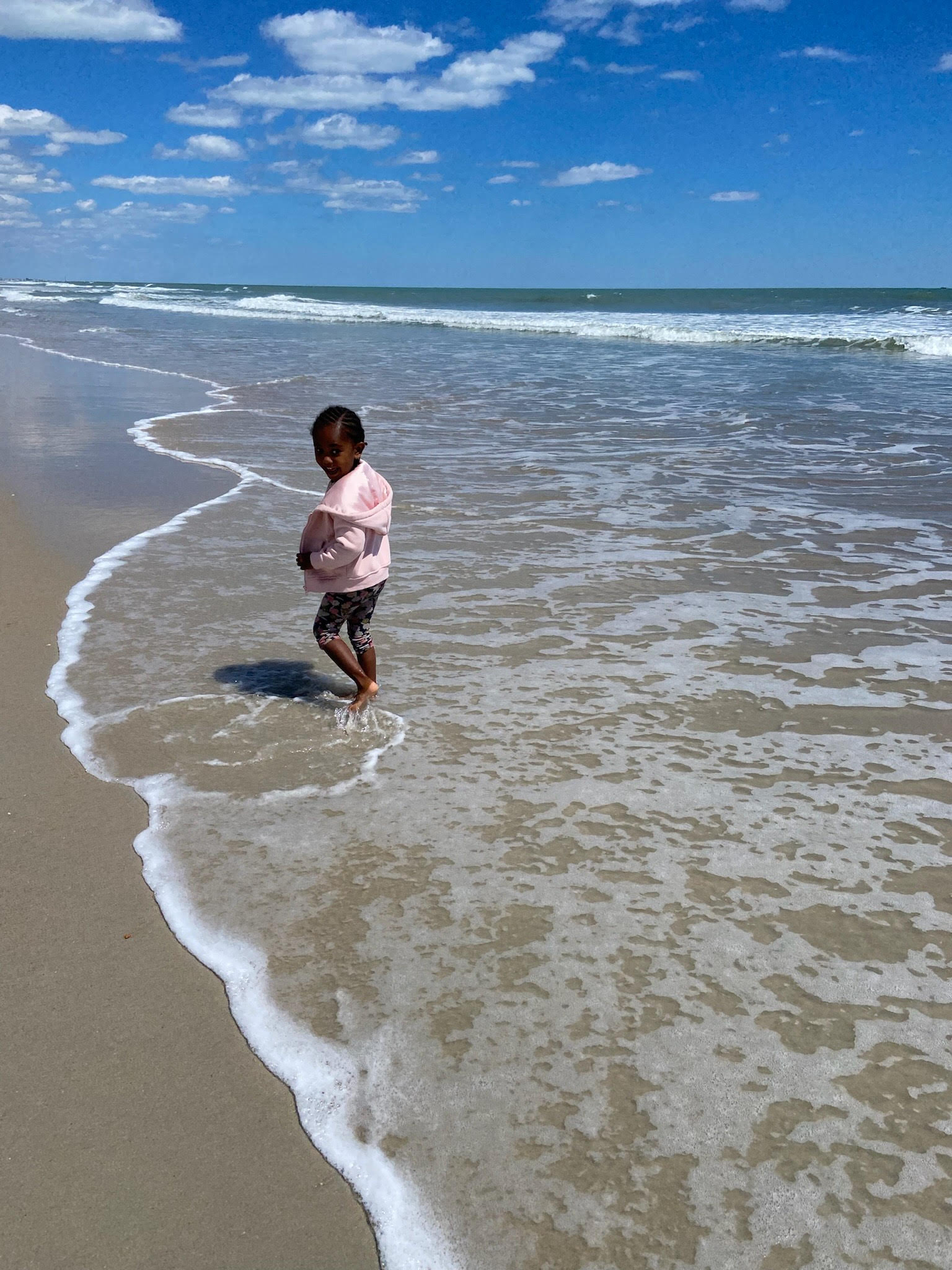 Child playing in the ocean on a sunny day.
