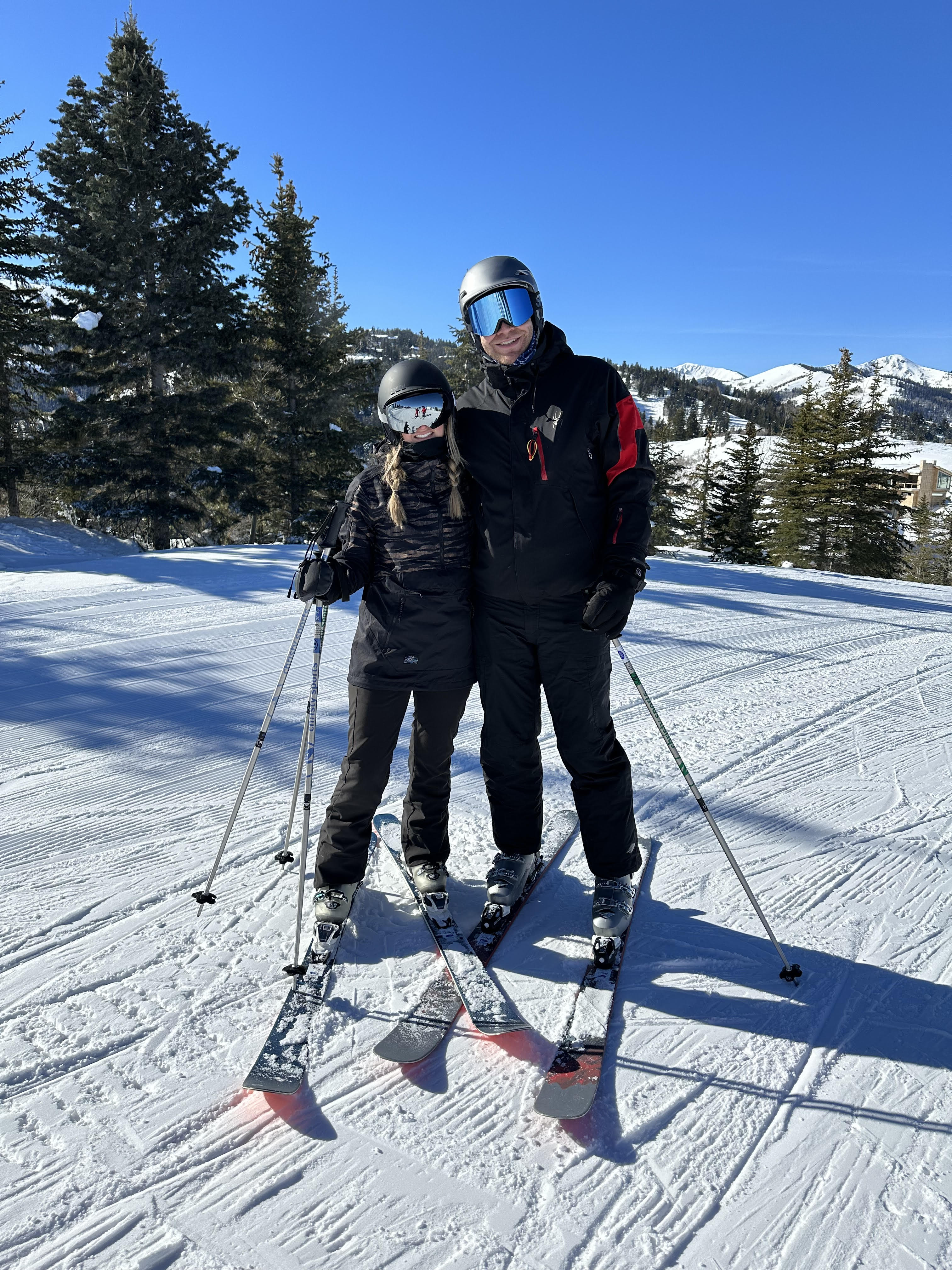 Advisor posing with another person on skis on a mountainside.