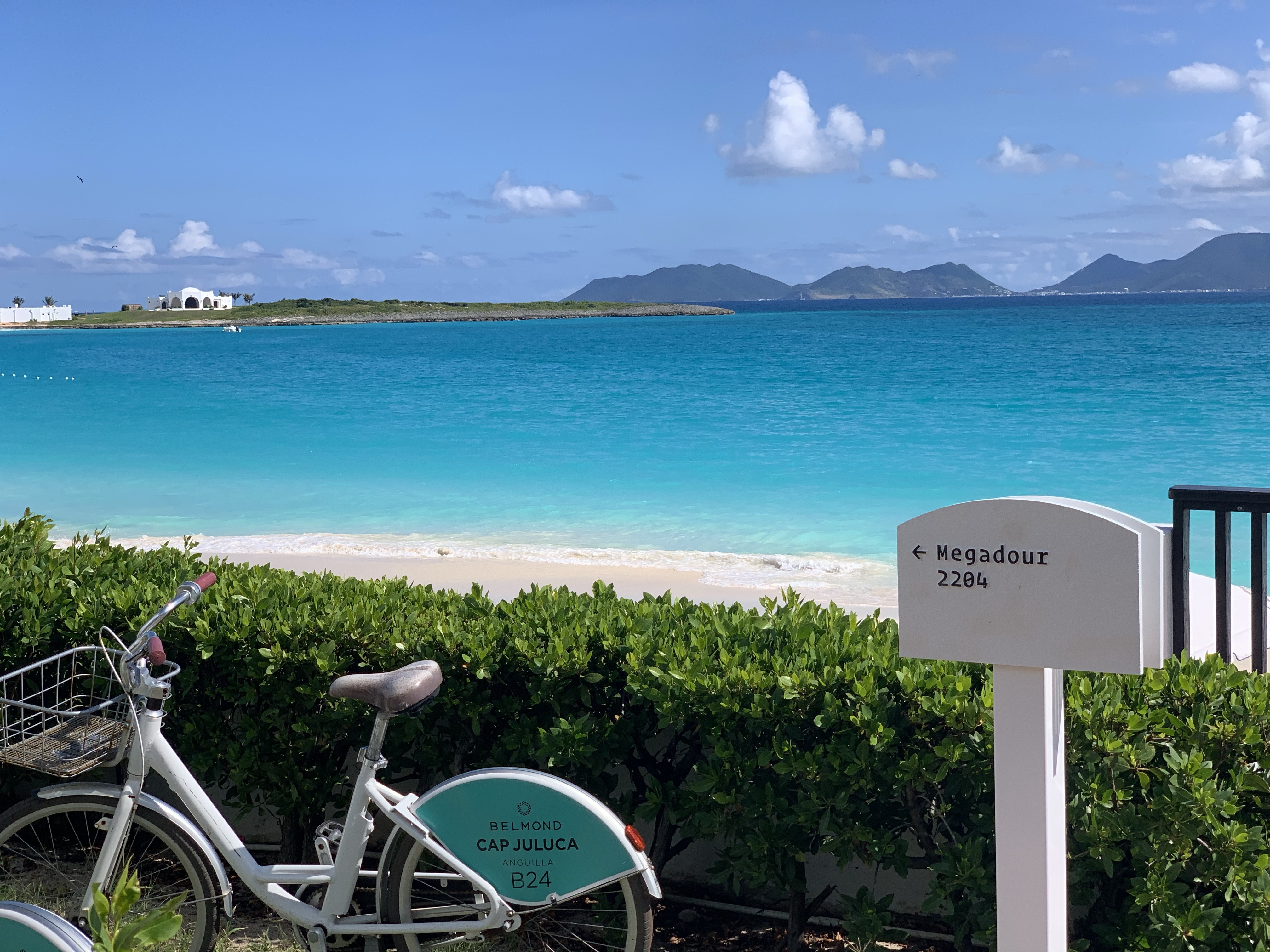 View of a bike from Cap Juluca resort parked by a beautiful white sand beach and turquoise sea