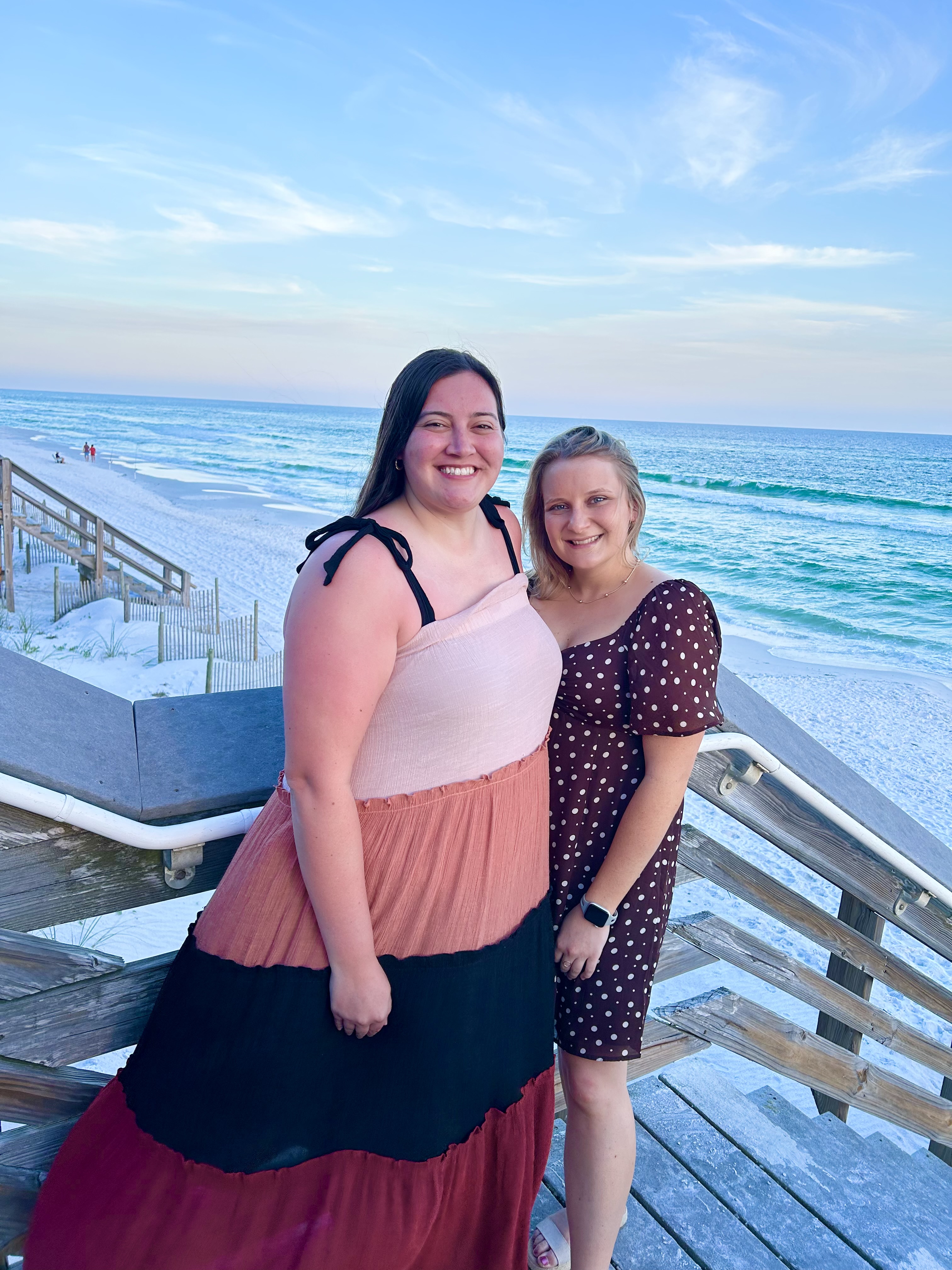 Advisor posing with friend on a pier leading to the beach during the daytime.