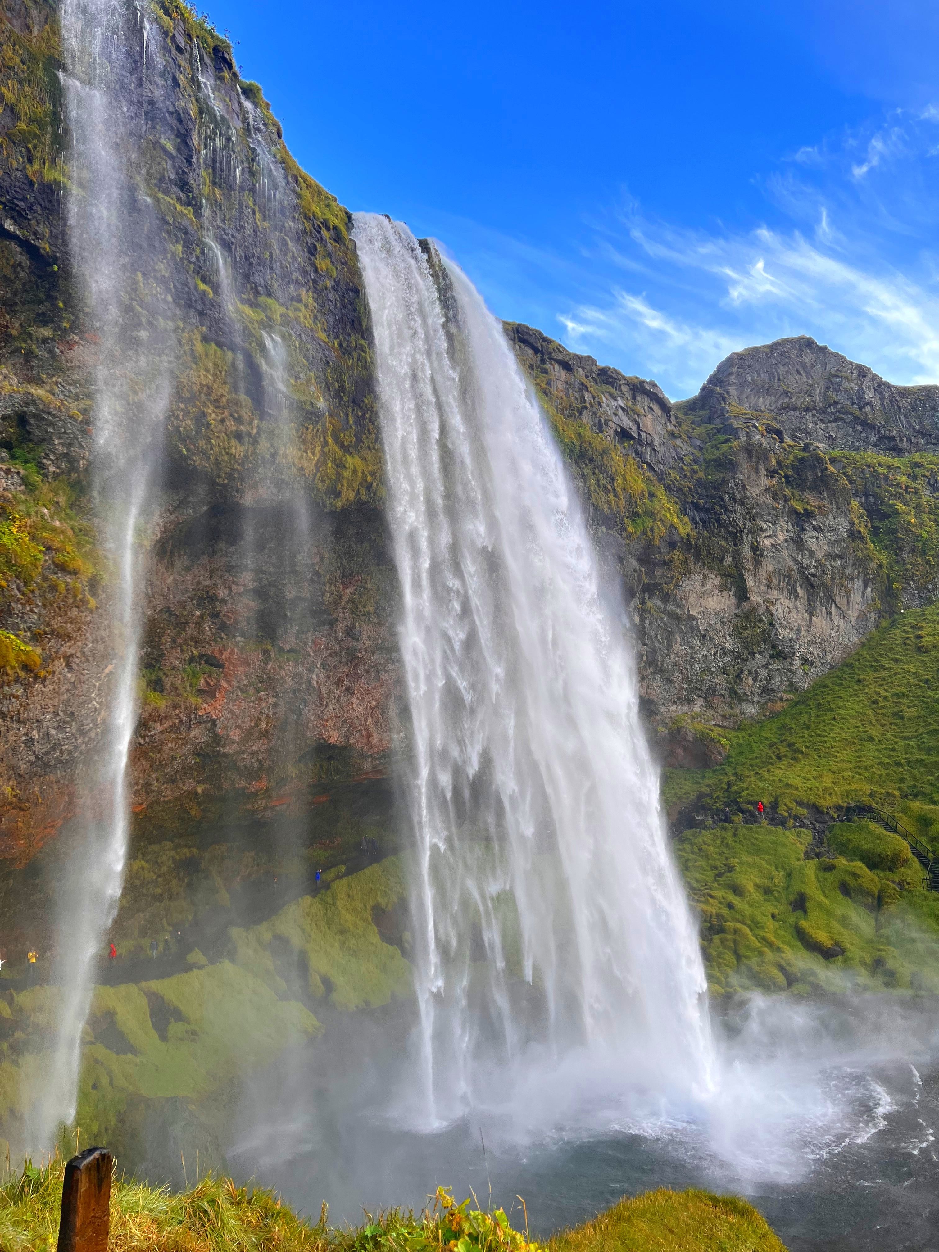 View of a beautiful tall waterfall cascading into a pool under sunny skies
