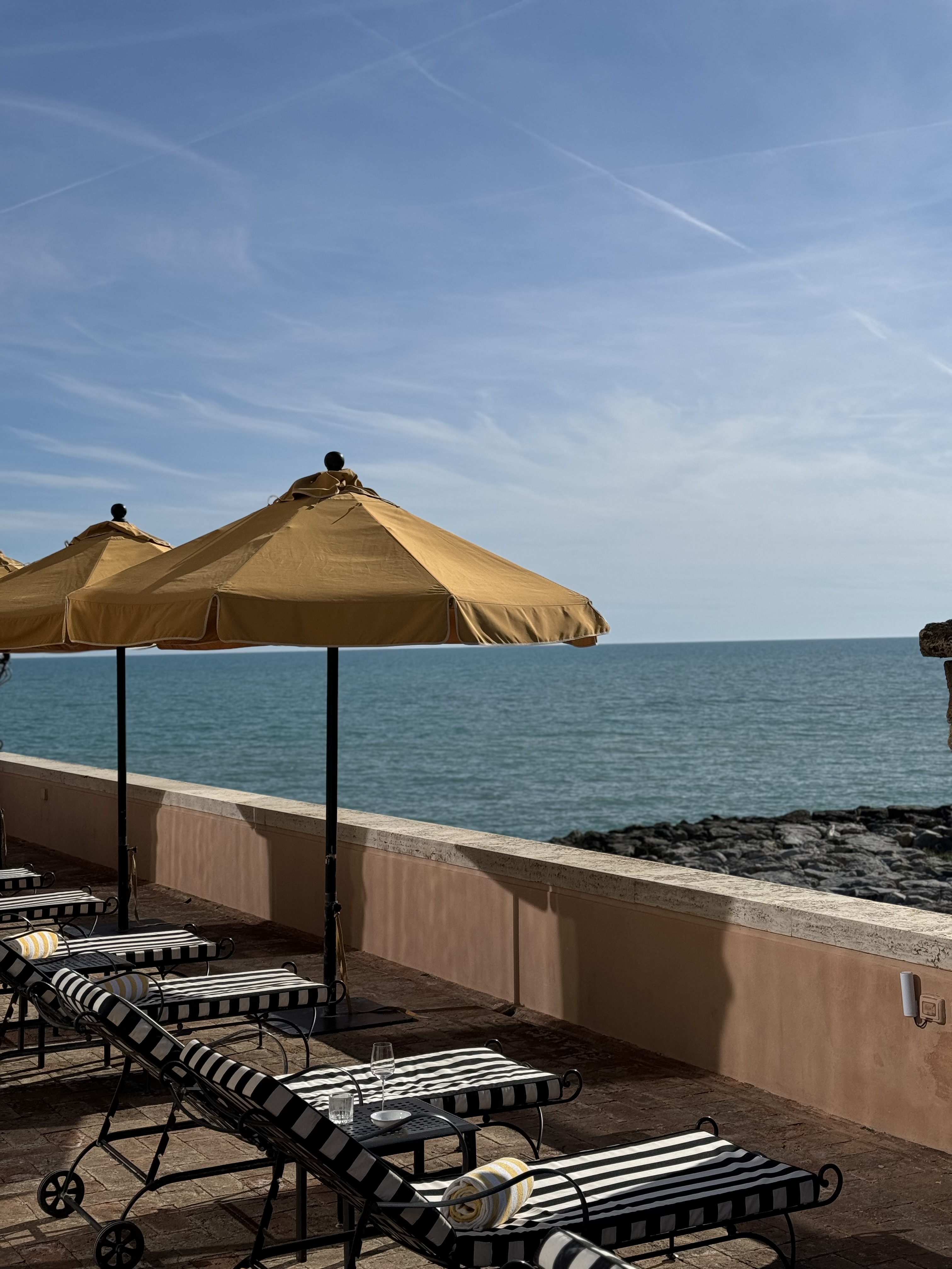 View of lounge chairs and yellow umbrellas looking out over the sea on a sunny day