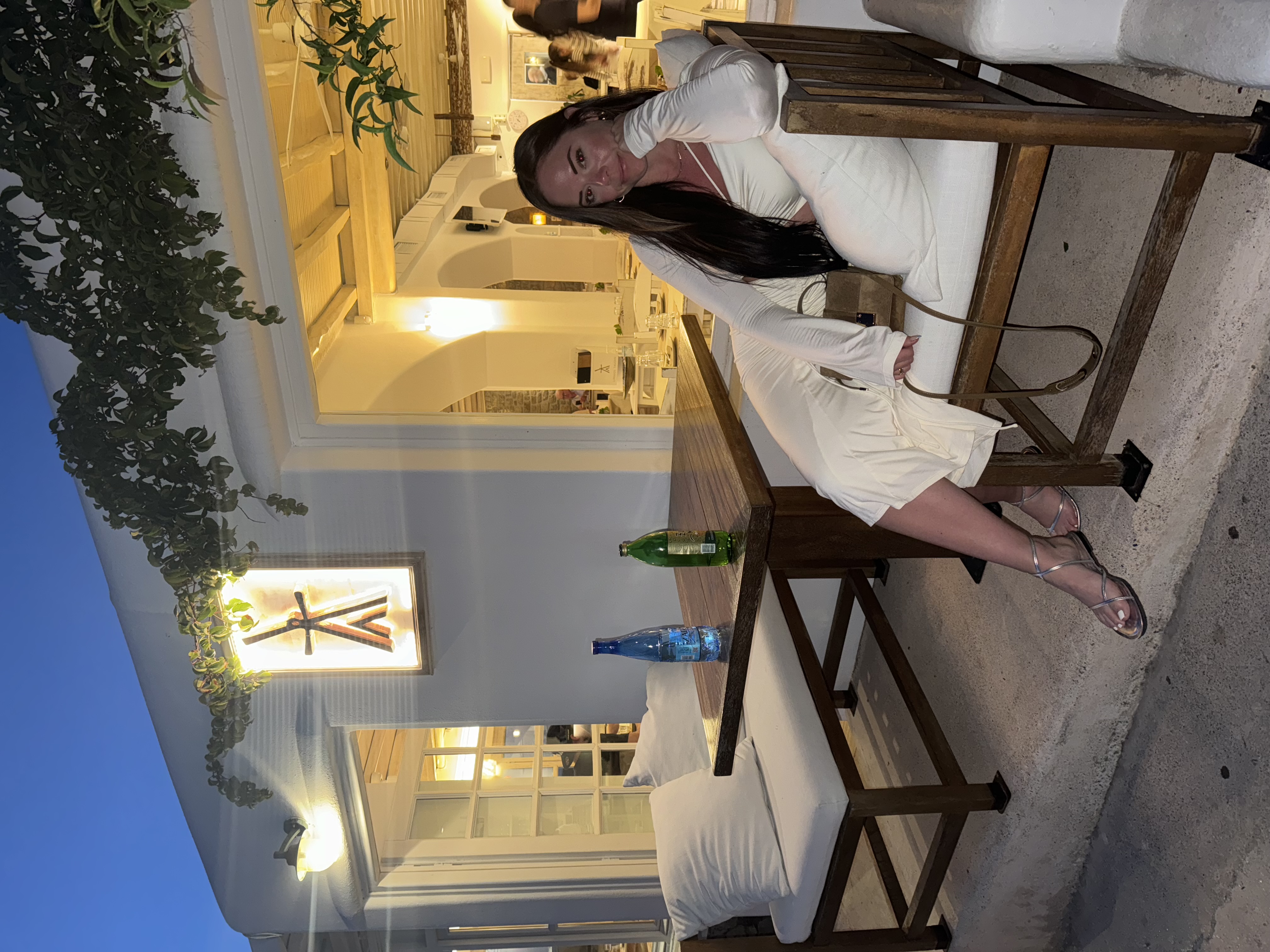 Advisor in a white dress sitting on a chair outdoors at a hotel lounge at night