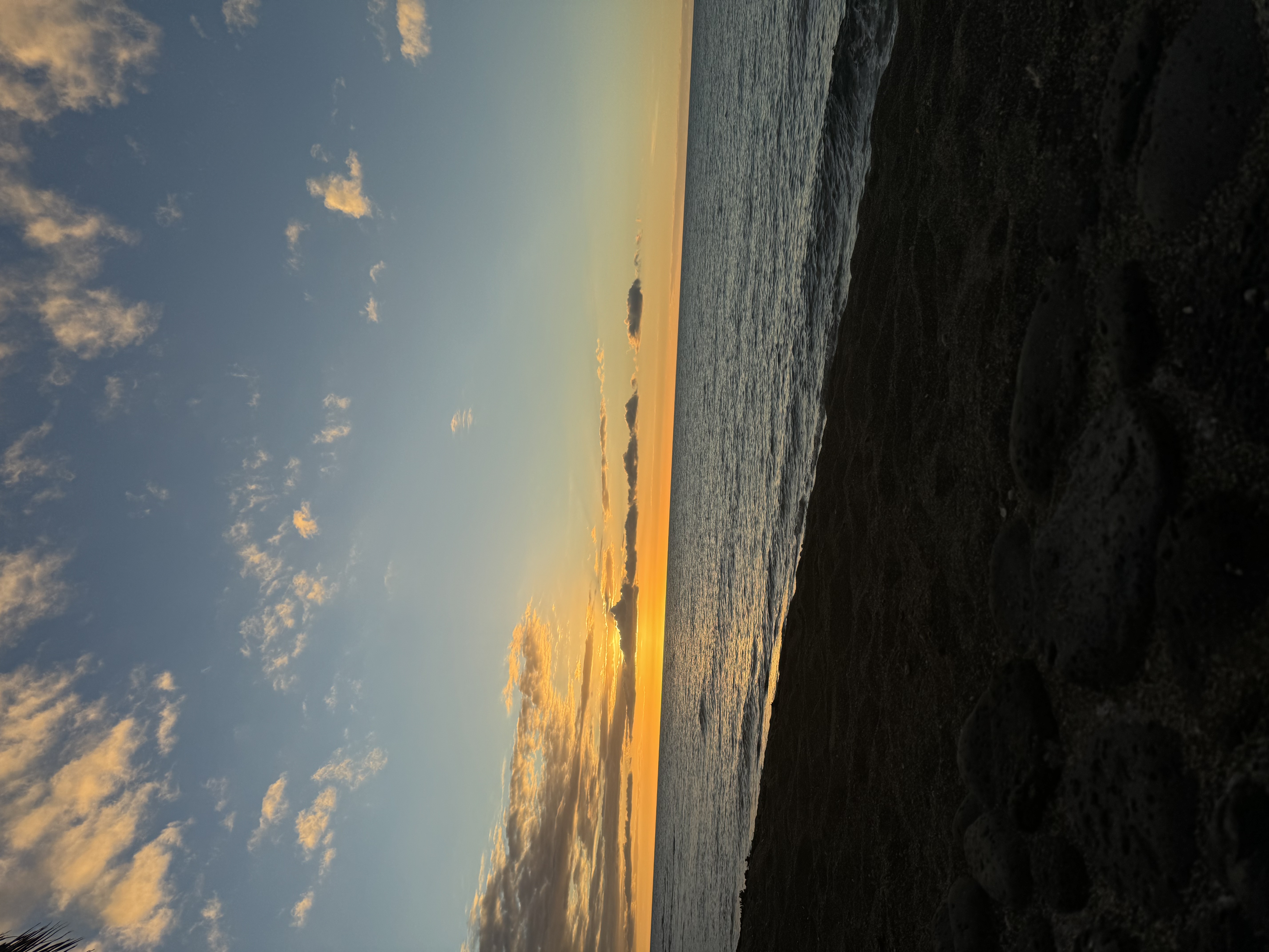 View of an orange and blue sunset on the horizon over a calm sea