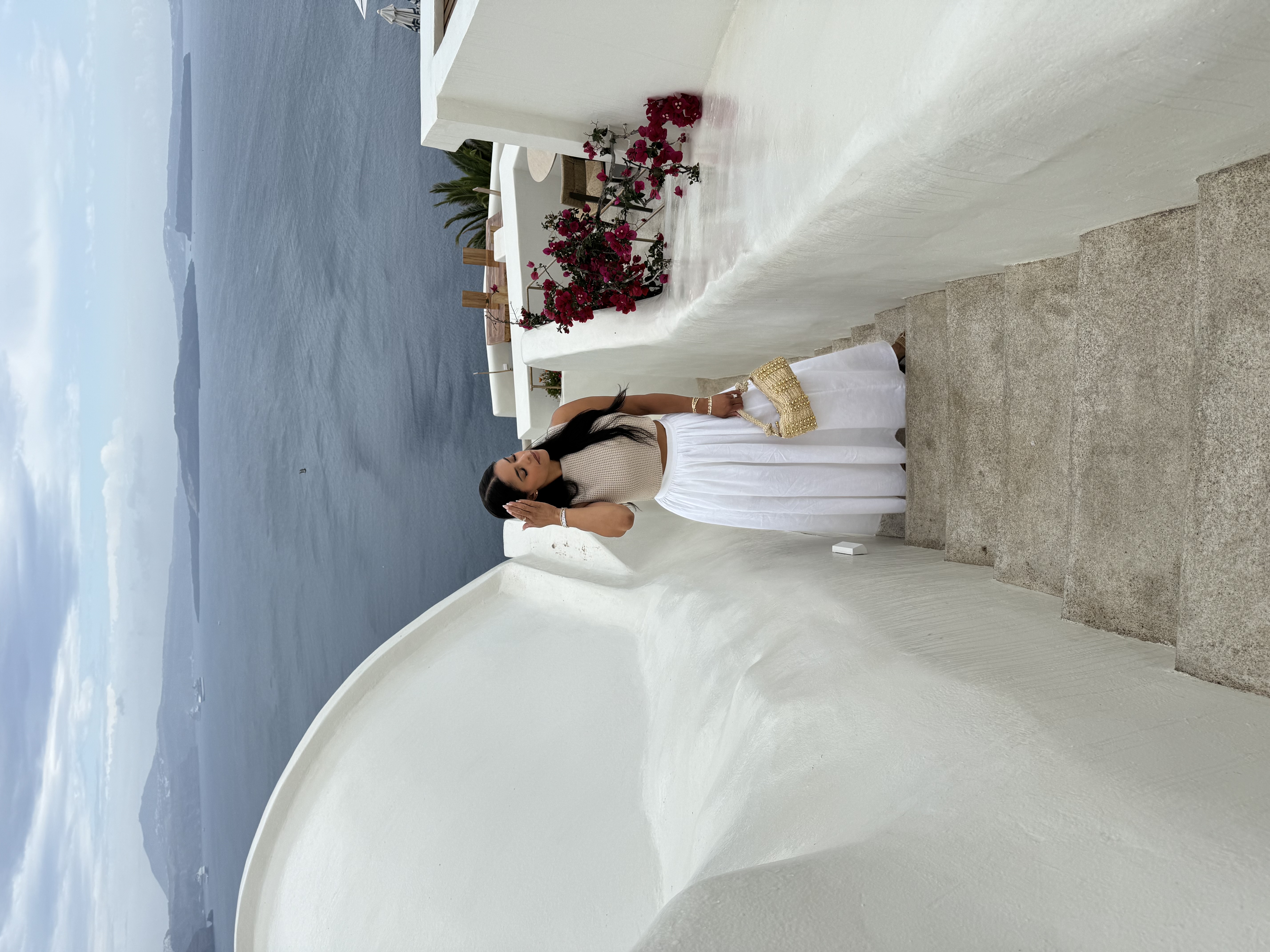 Advisor in a long white skirt seen from above climbing stairs overlooking the sea