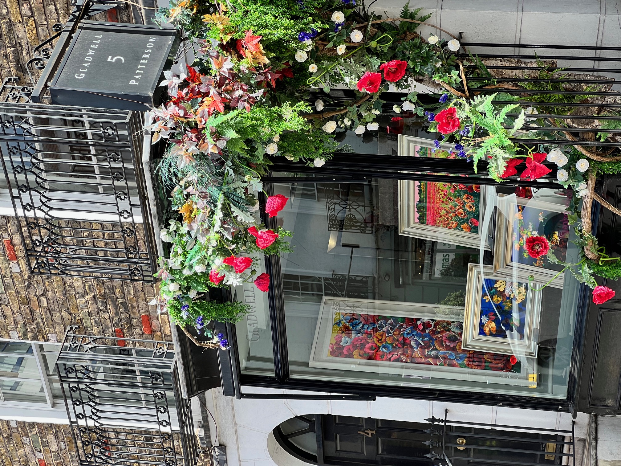 View of a glass window storefront on a street corner decorated with a beautiful flower display