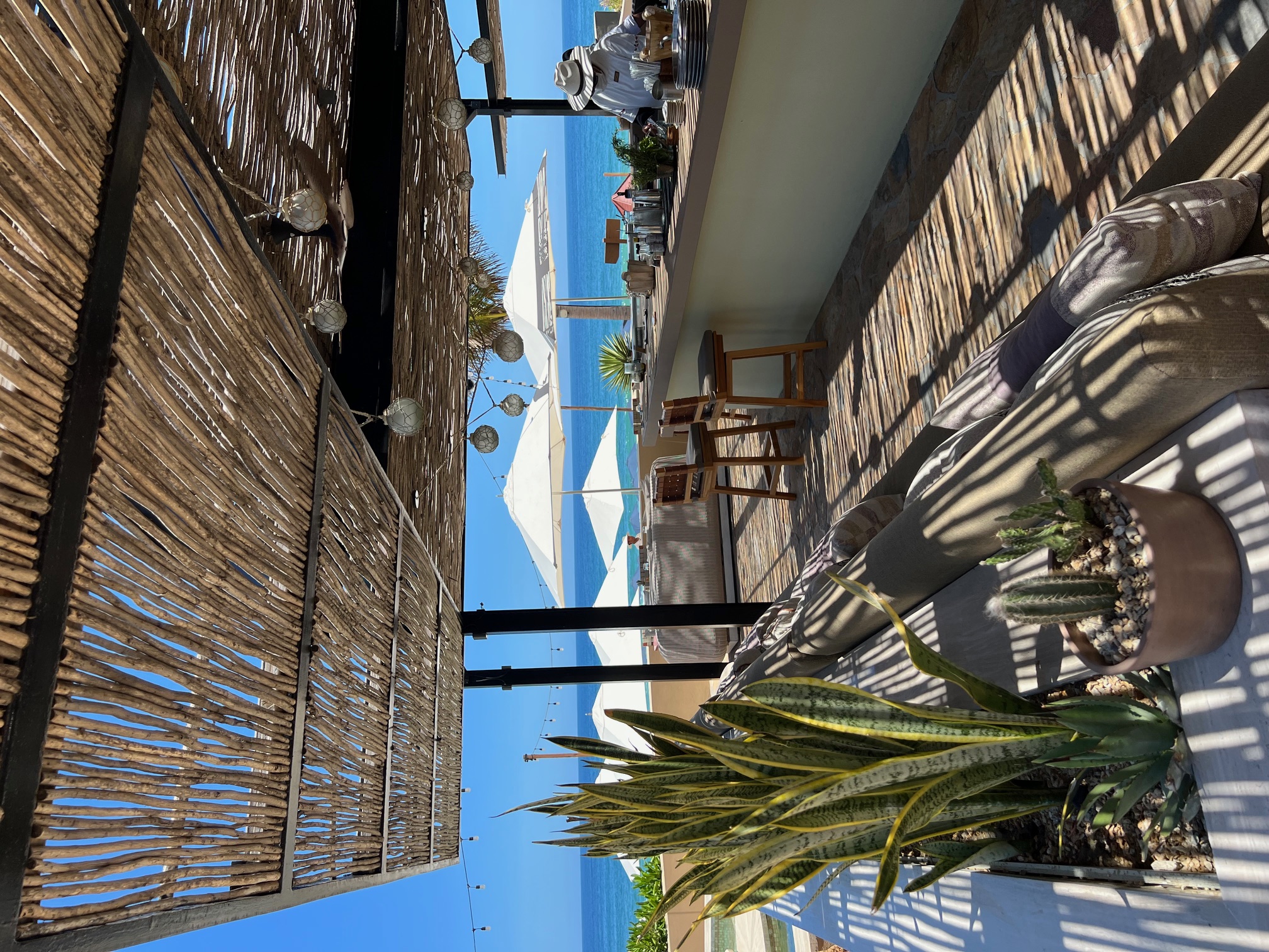 View of a resort bar covered by a thatched roof overlooking the sea on a sunny day