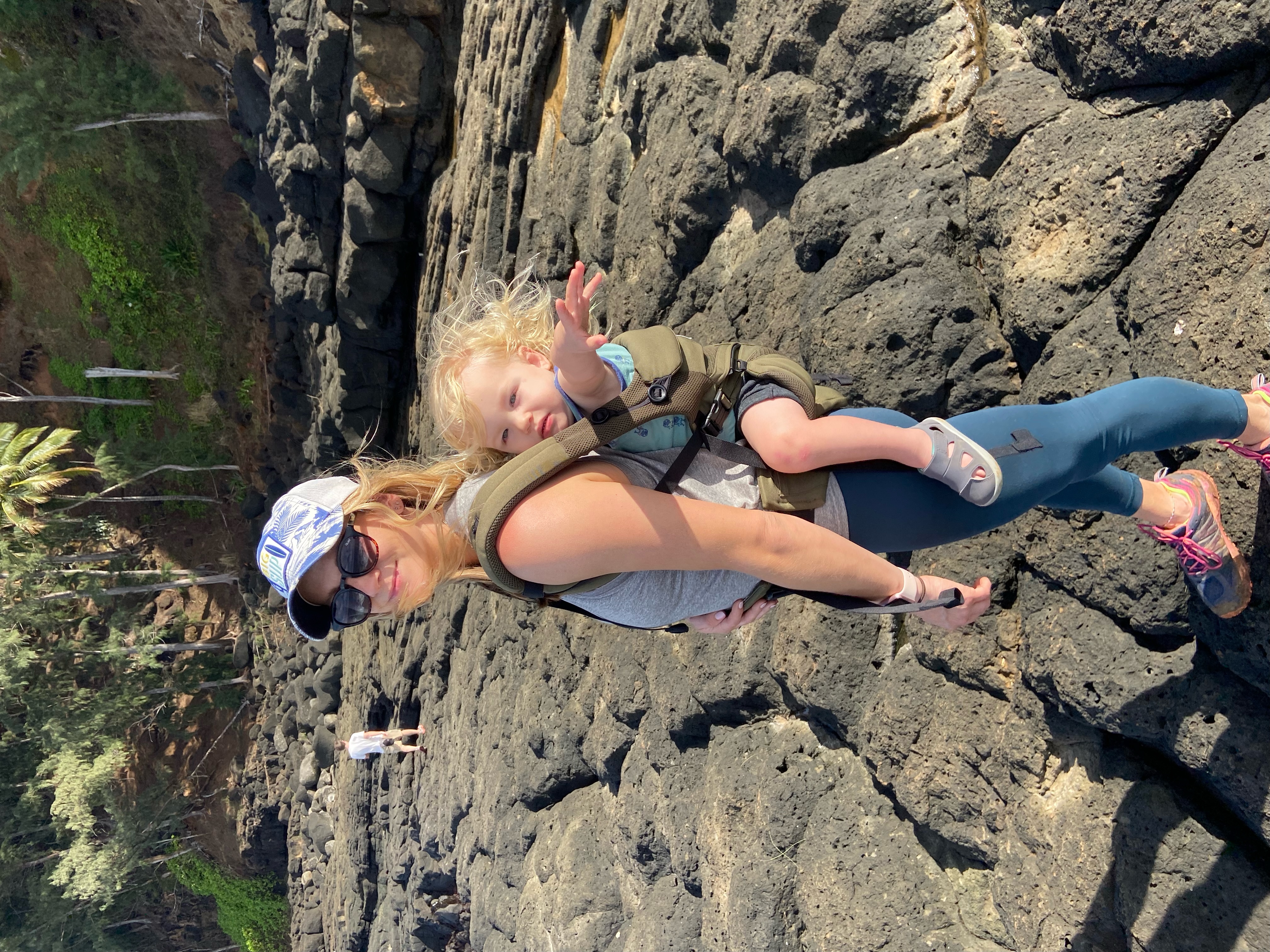 Advisor with a baby strapped to her back on a rocky landscape