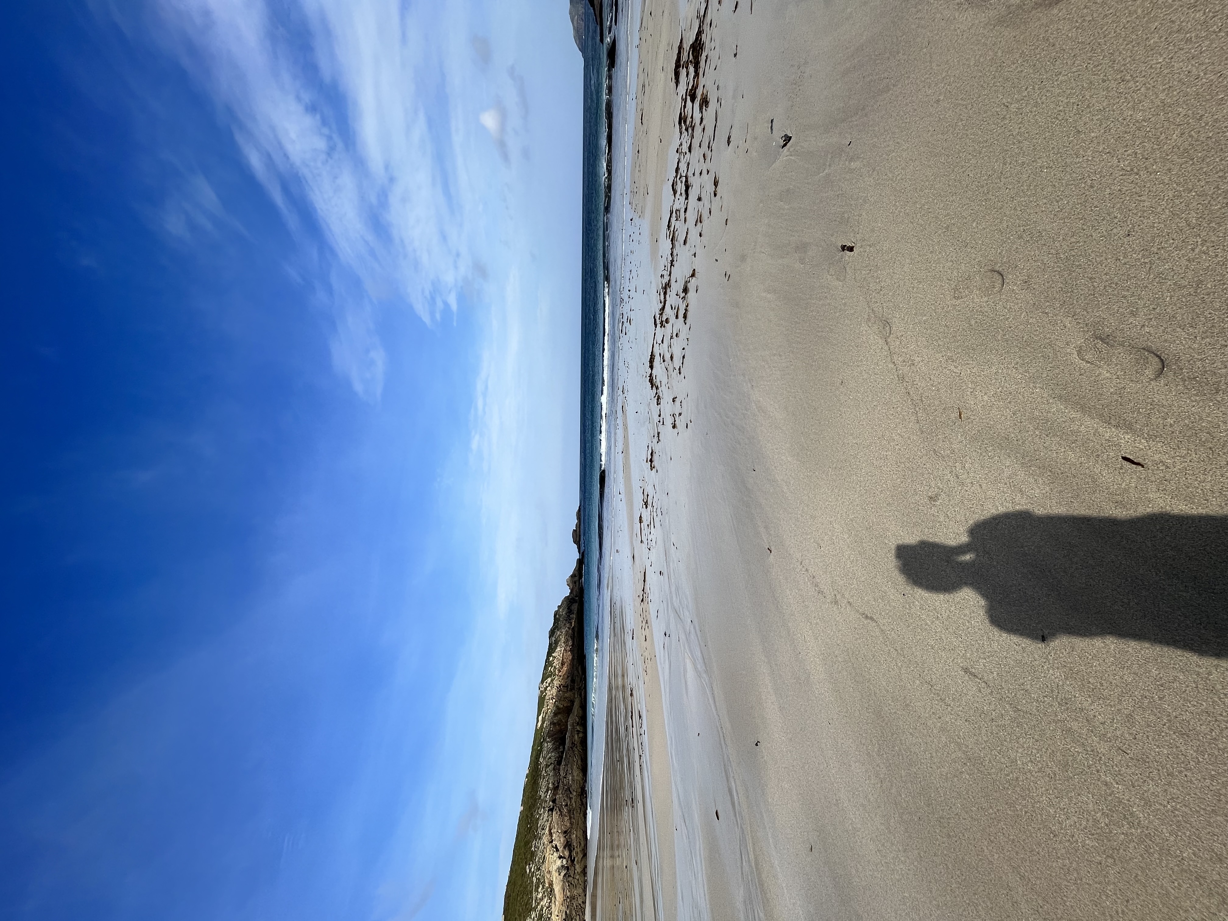 View of advisor’s shadow taking a photo of an empty beach under sunny skies