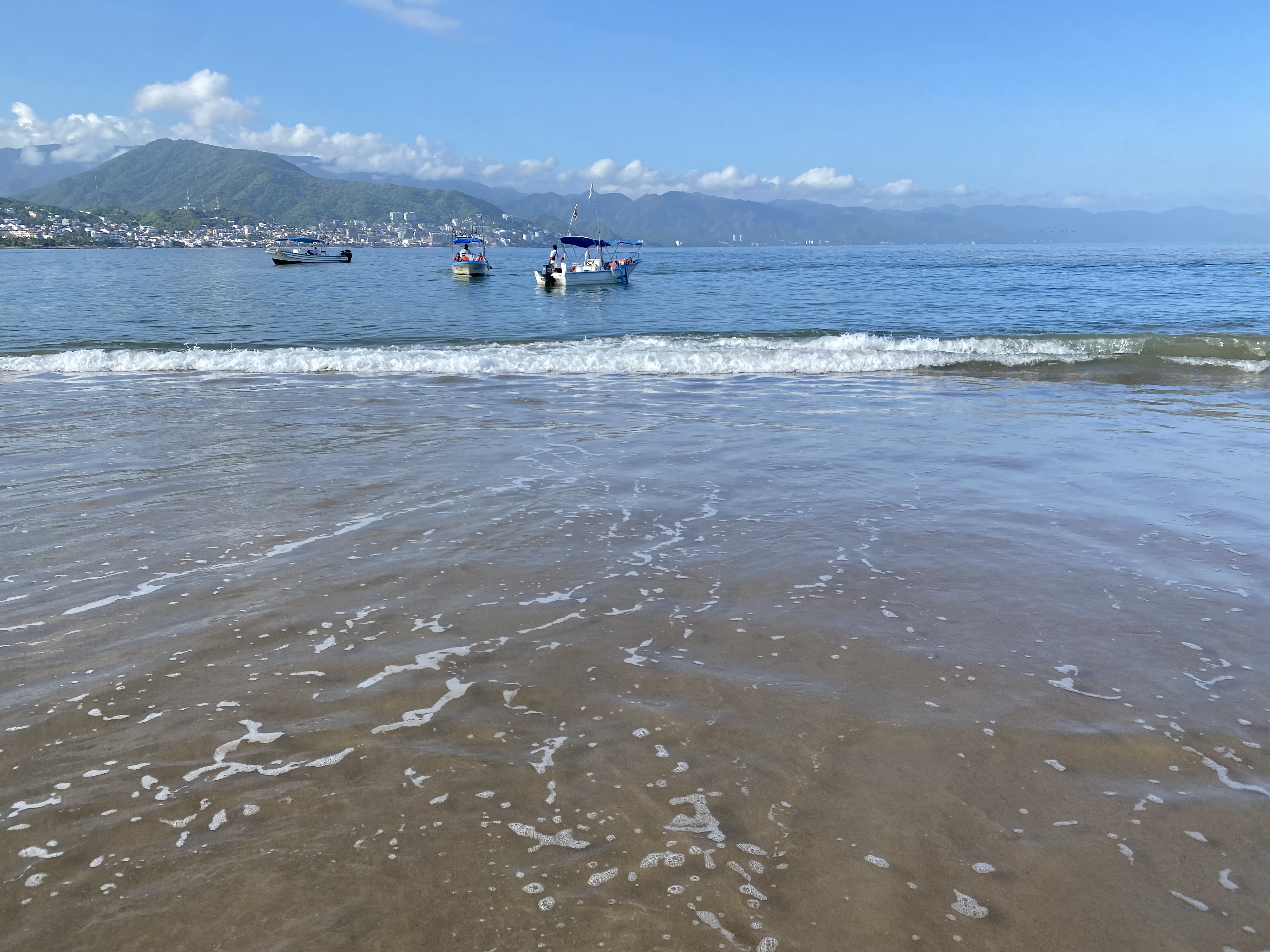 Photo of the ocean with boats along the shore during the daytime.
